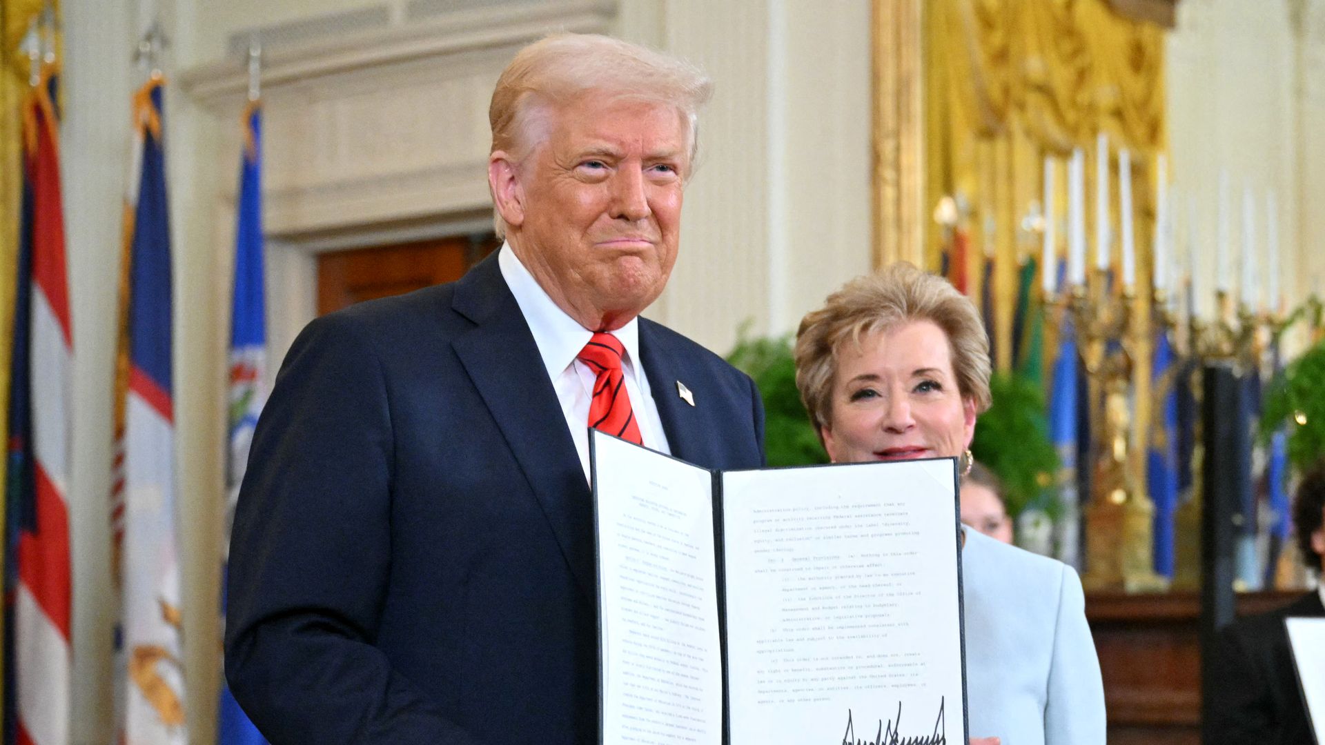 President Trump holds up a signed document with Linda McMahon.