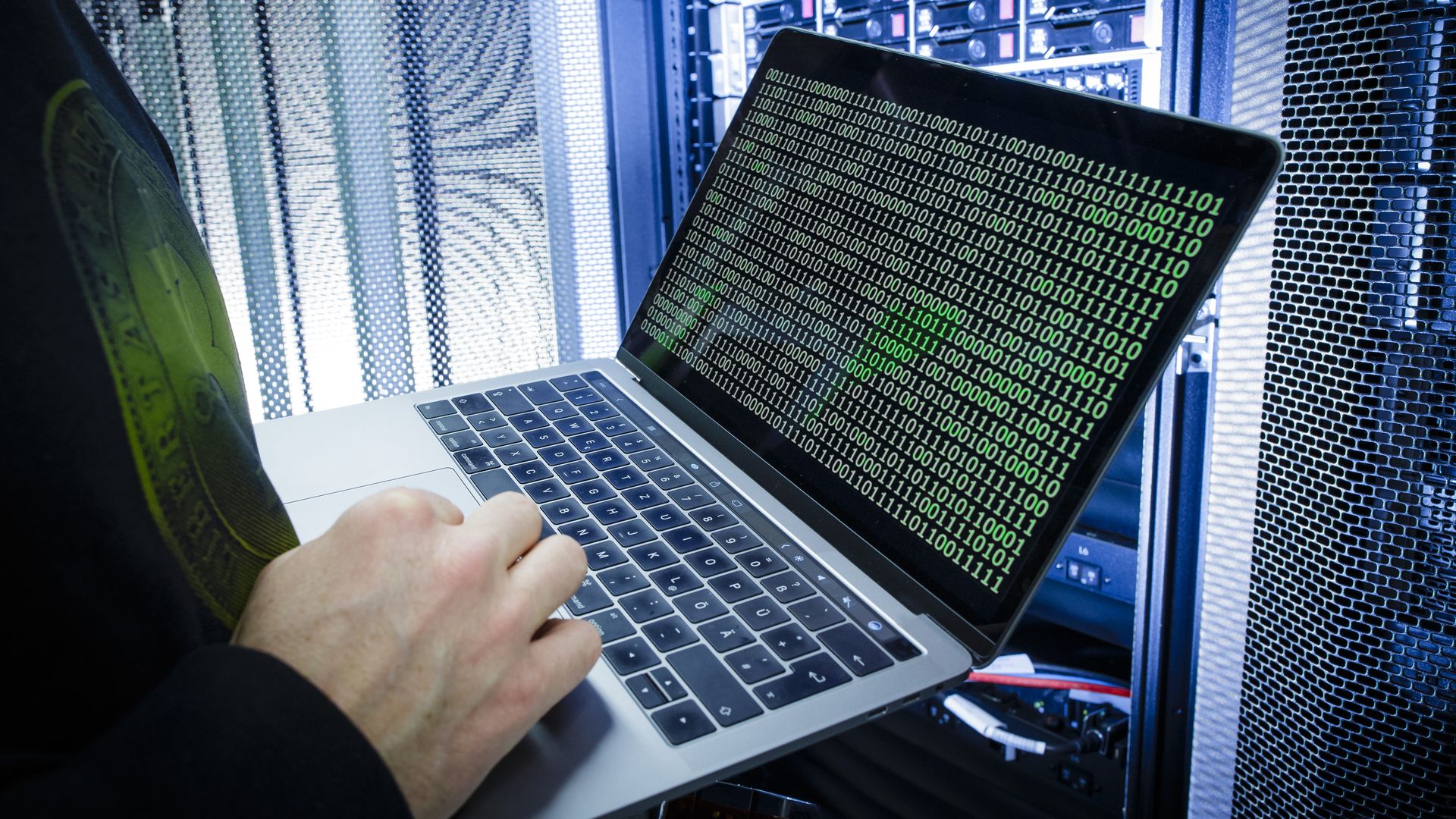 Man types on computer with green 1s and 0s on it