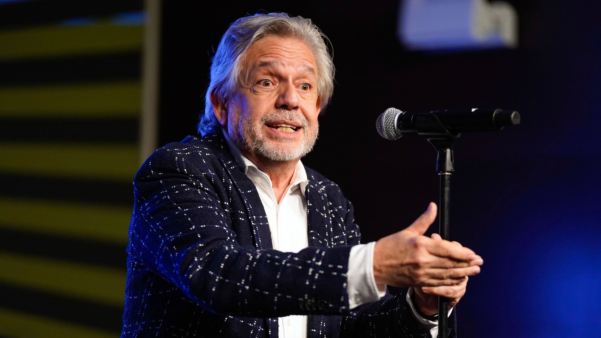 Luis A. Miranda gestures using his right hand while standing in front of a microphone