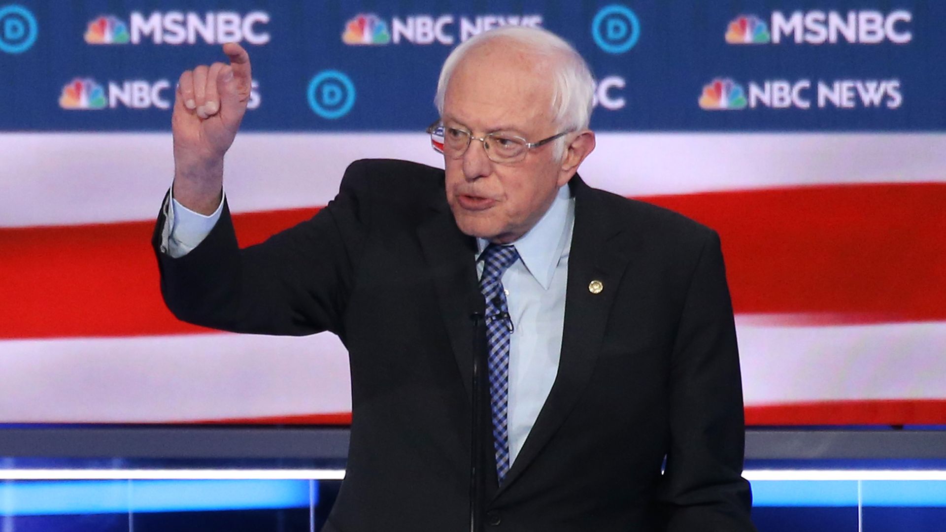 In this image, Sanders stands behind a podium on the debate stage