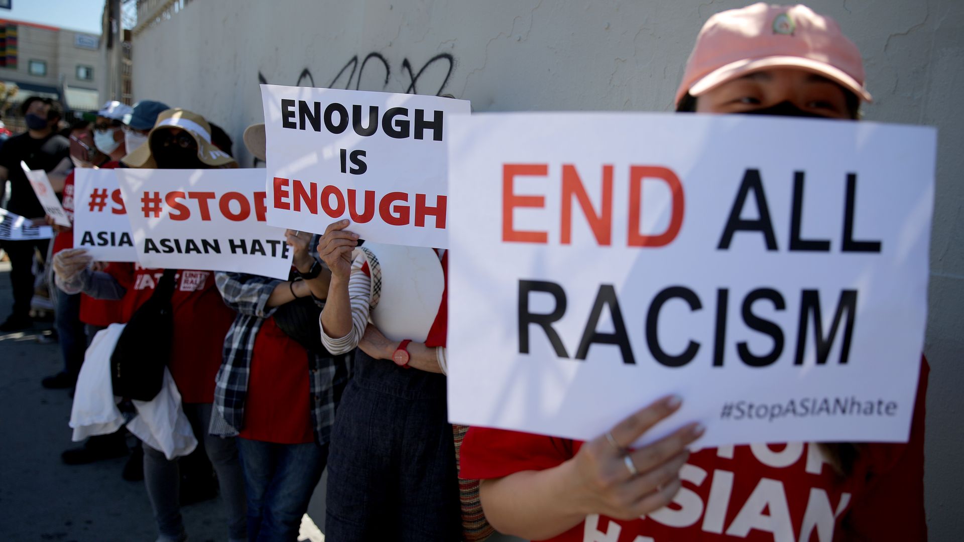 Photo of protesters holding signs that say: "End Racism," "Enough is Enough," and "Stop Asian Hate"