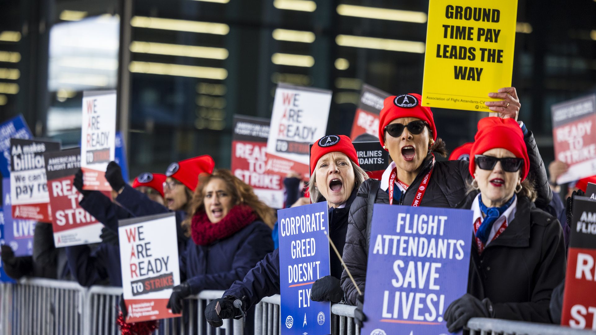 A group of people lined up and holding signs that read "Flight attendants save lives"