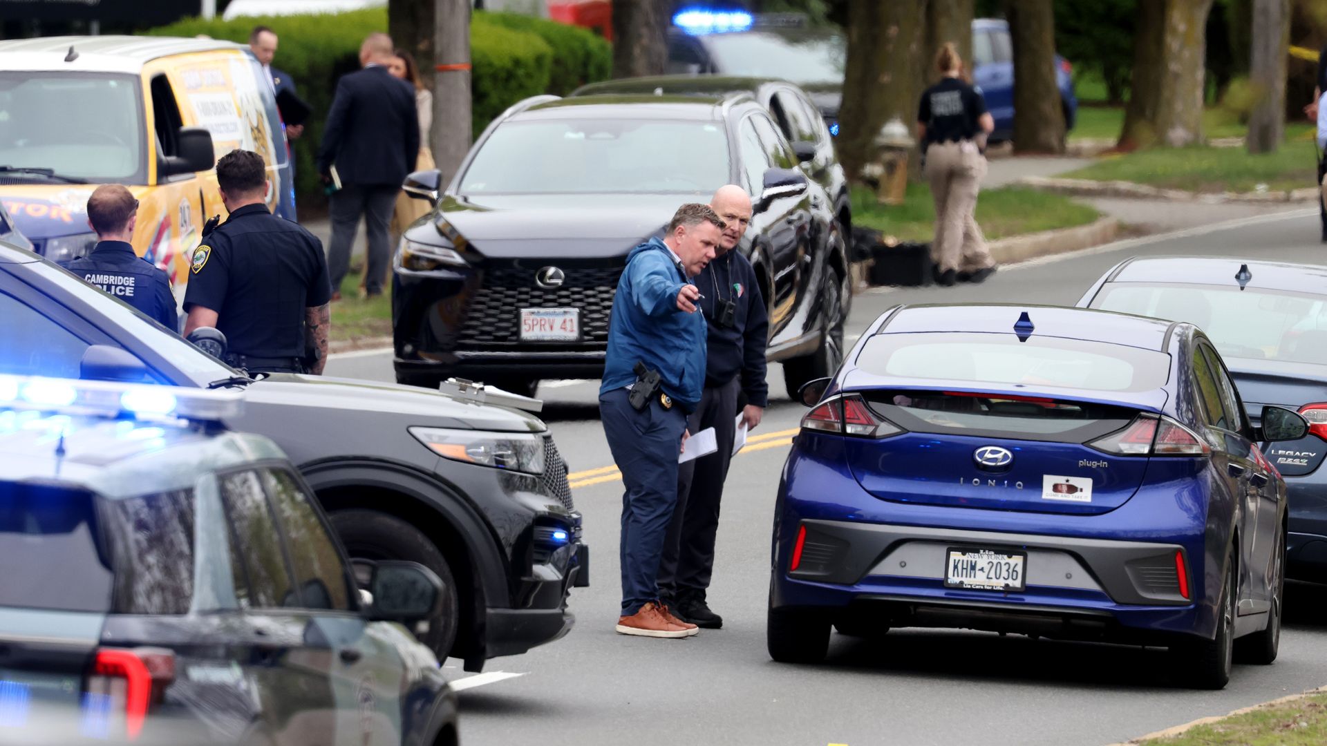 Police officers speak with people seated inside a car on a Cambridge street.