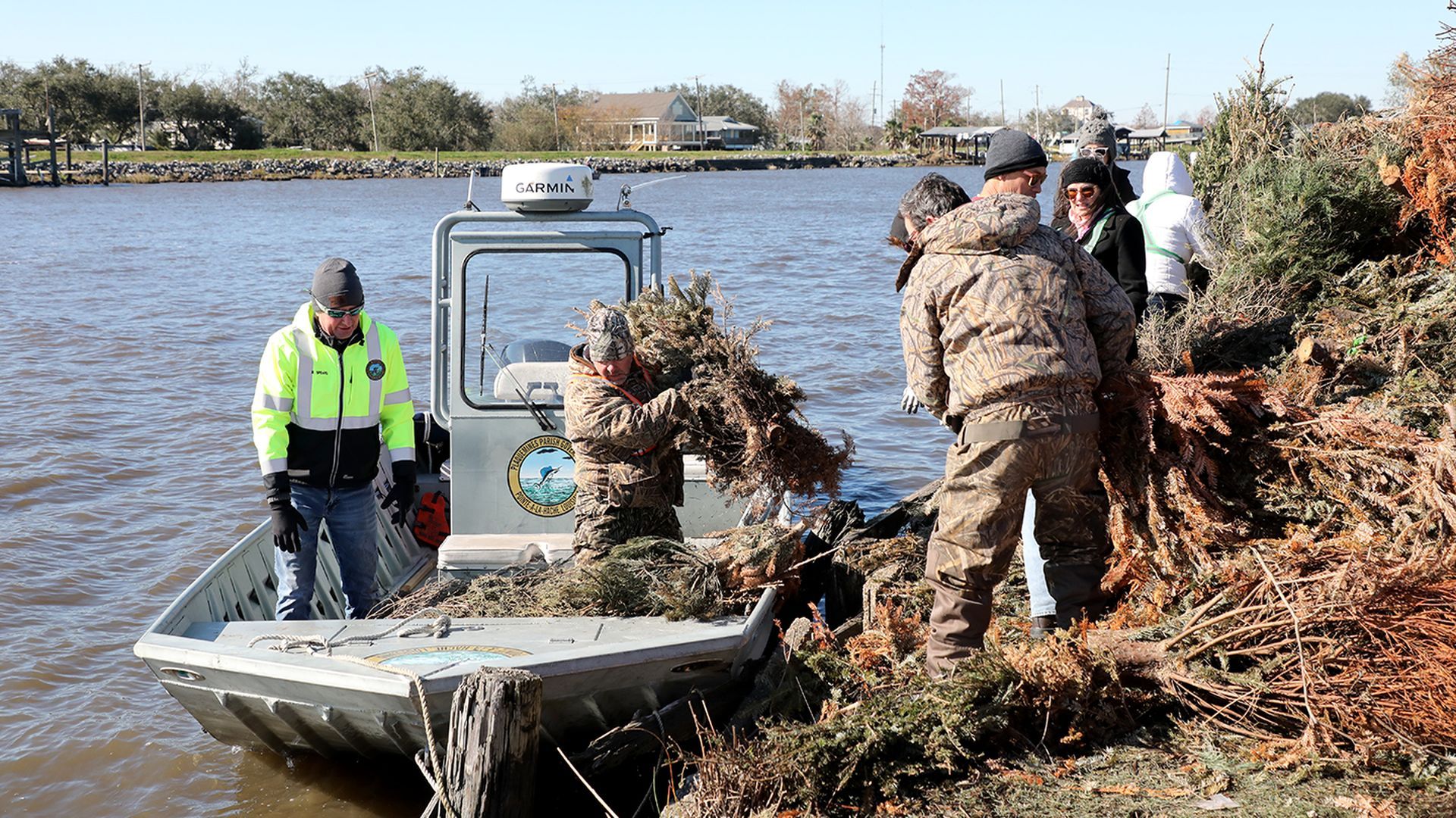 Image shows people putting trees onto a boat.