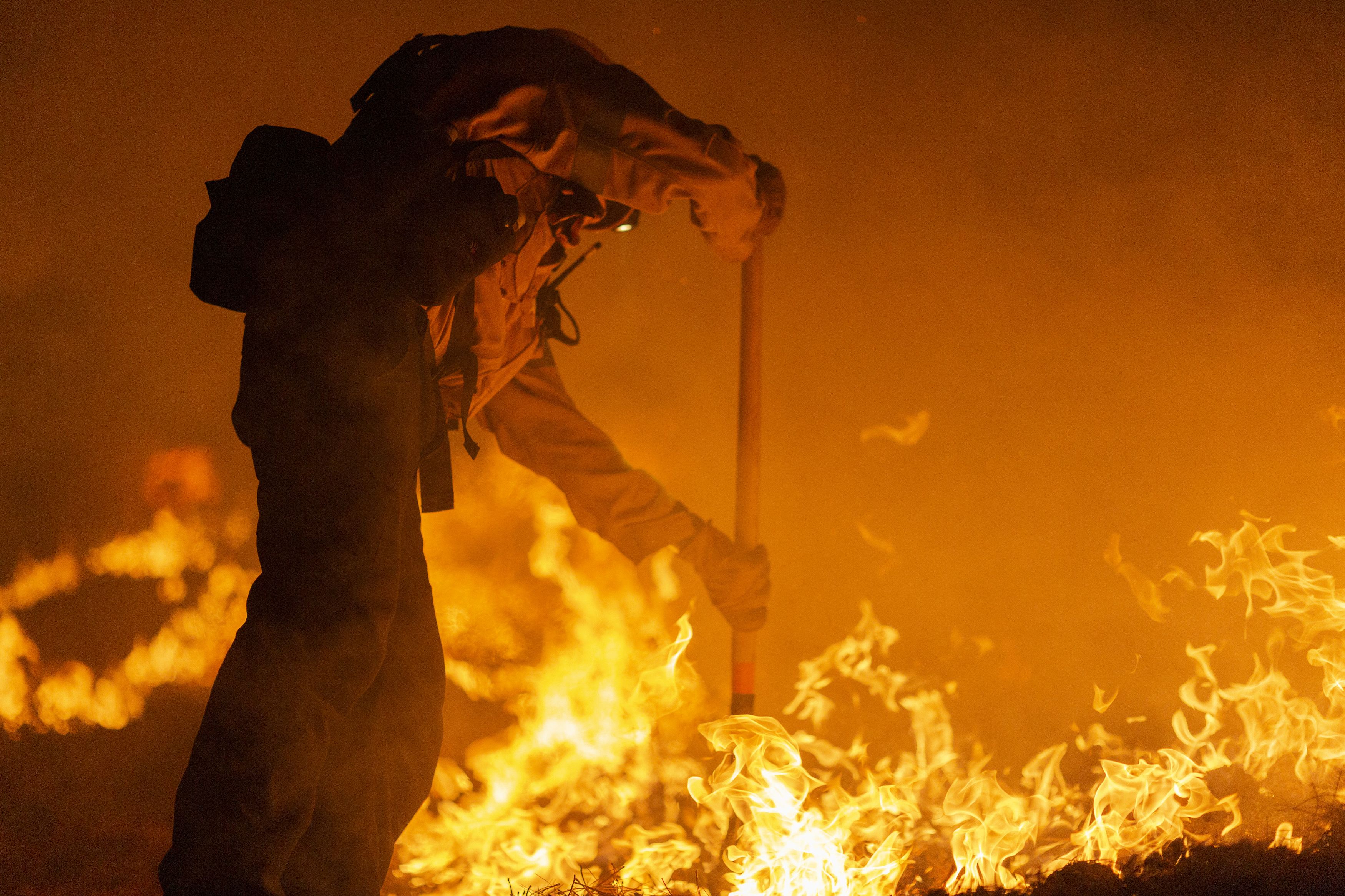 Los Angeles County firefighters, using only hand tools, keep fire from jumping a fire break at the Bobcat Fire in the Angeles National Forest 
