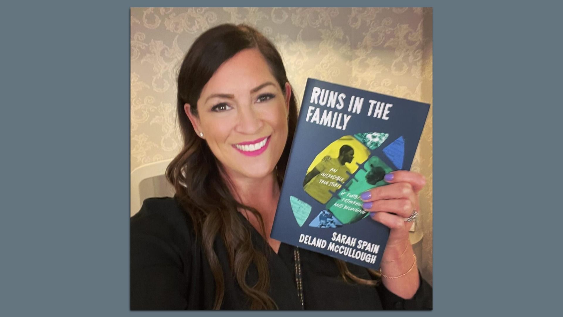 Photo of a woman holding up a book and posing. 