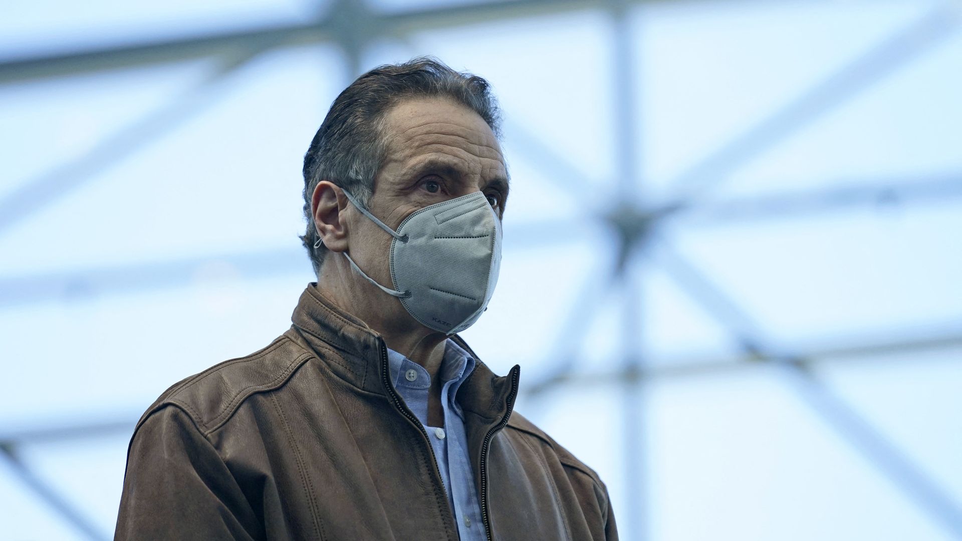 Andrew Cuomo wears a jacket and a face mask