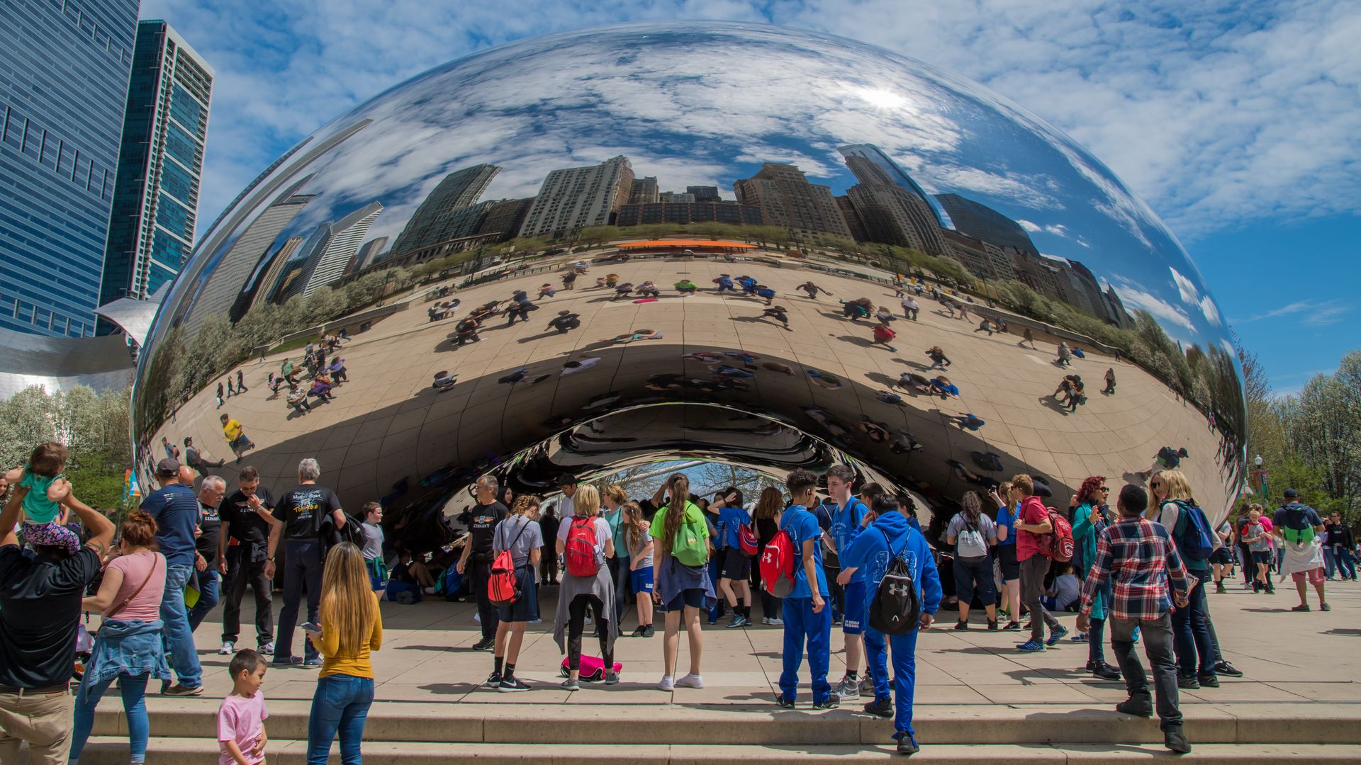 Chicago's Cloudgate, or "The Bean" with reflection of skyline and people standing around it.