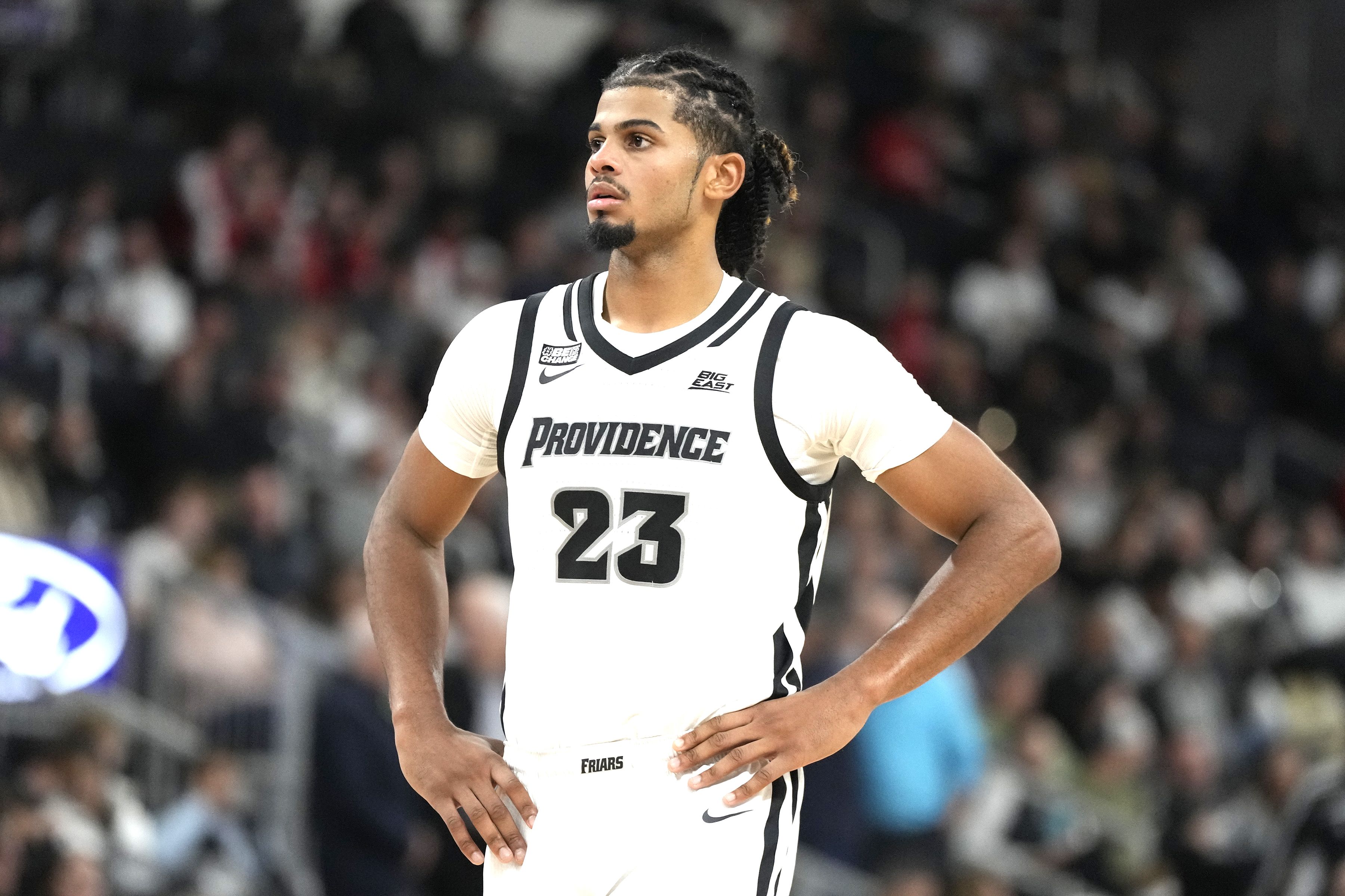 Photo of a basketball player on the court with his hands on his hips. 