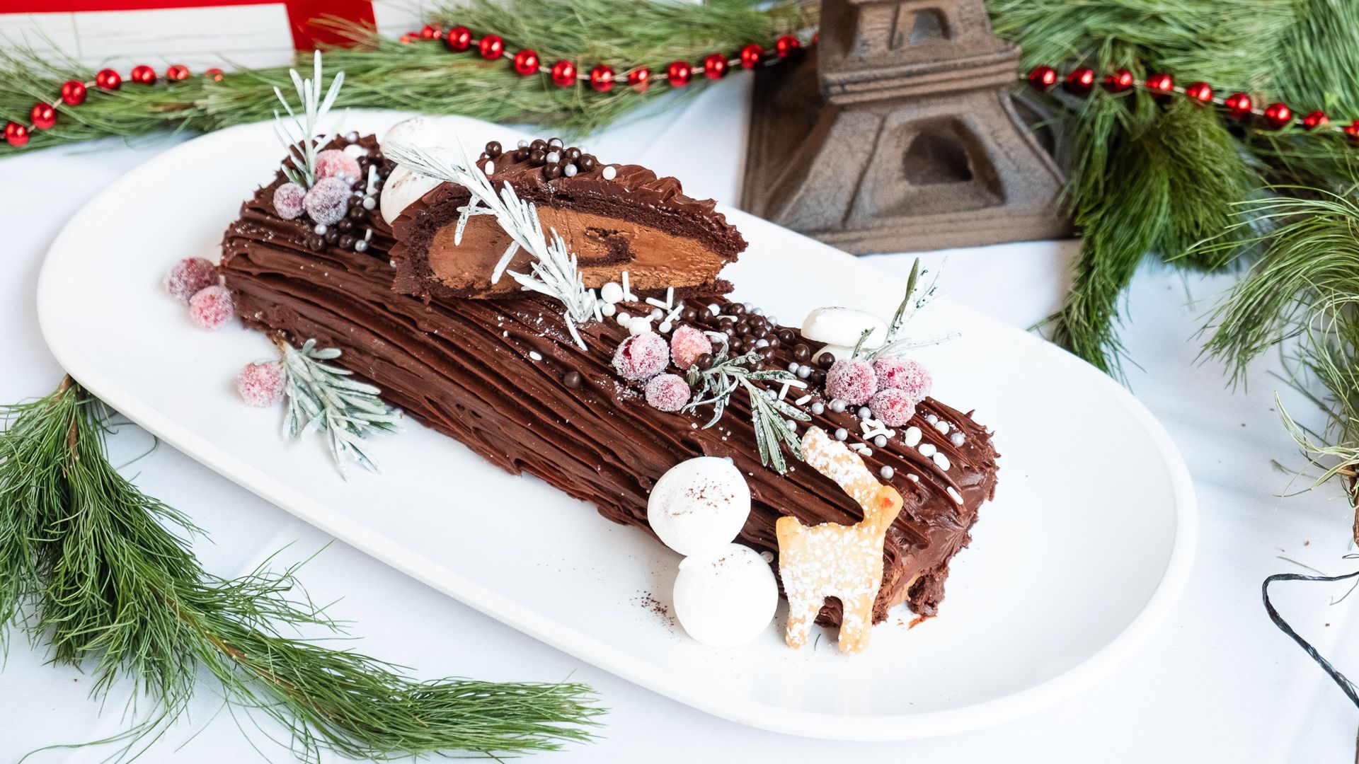 A chocolate yuletide cake on a white platter.