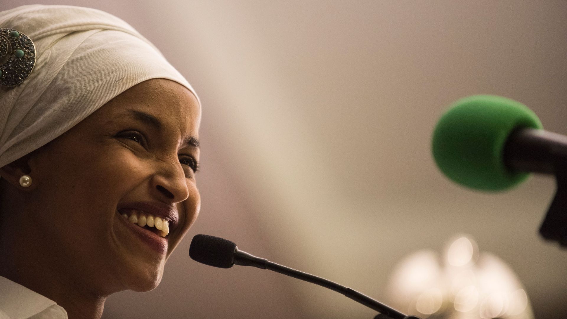 Ilhan Omar smiling at a microphone.