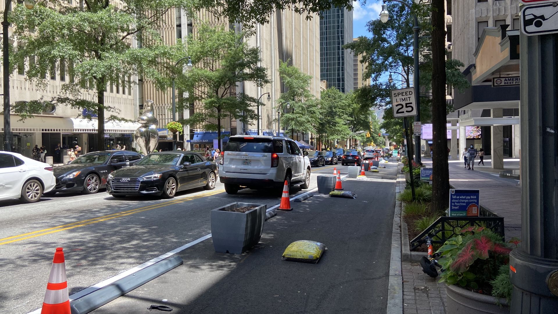 A photograph of a street with two far lanes blocked off with cones and wheel stops and planters to create a buffer between pedestrians and cars.