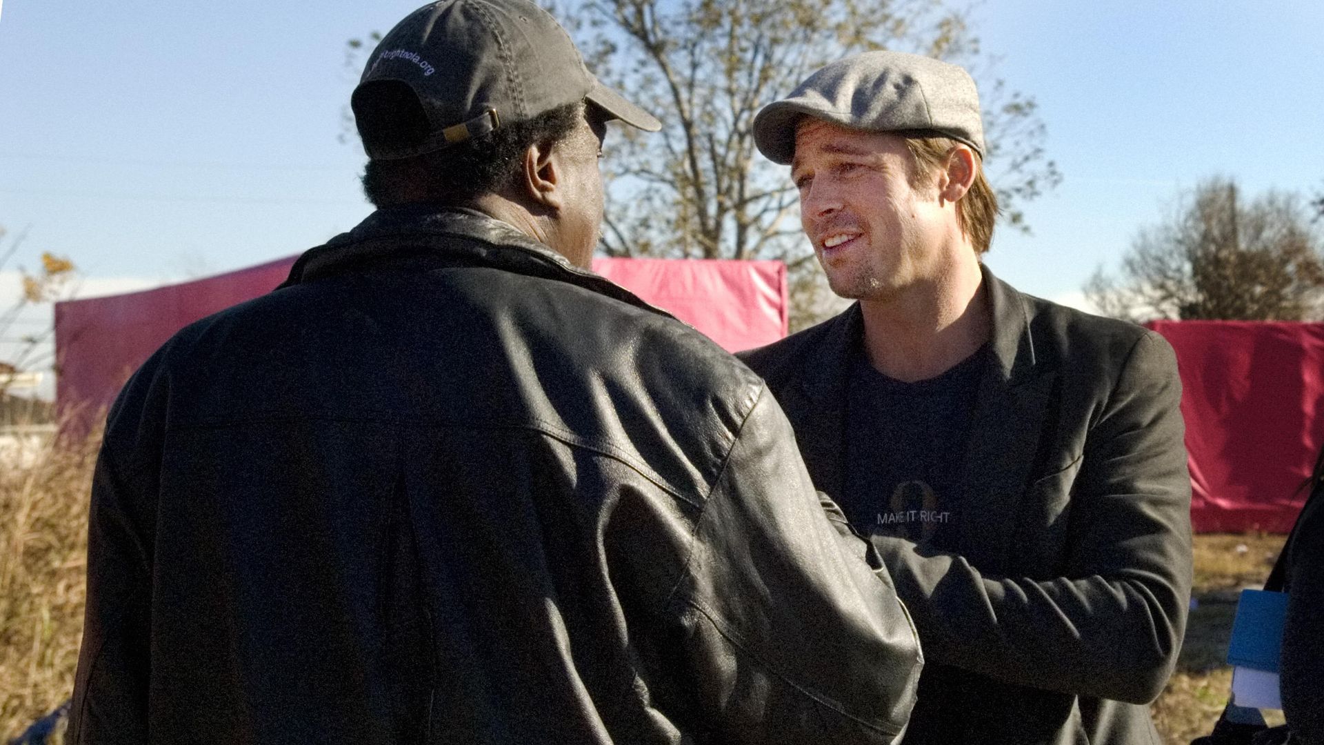 Actor Brad Pitt shakes the hand of Robert Green, who has his back to the camera.