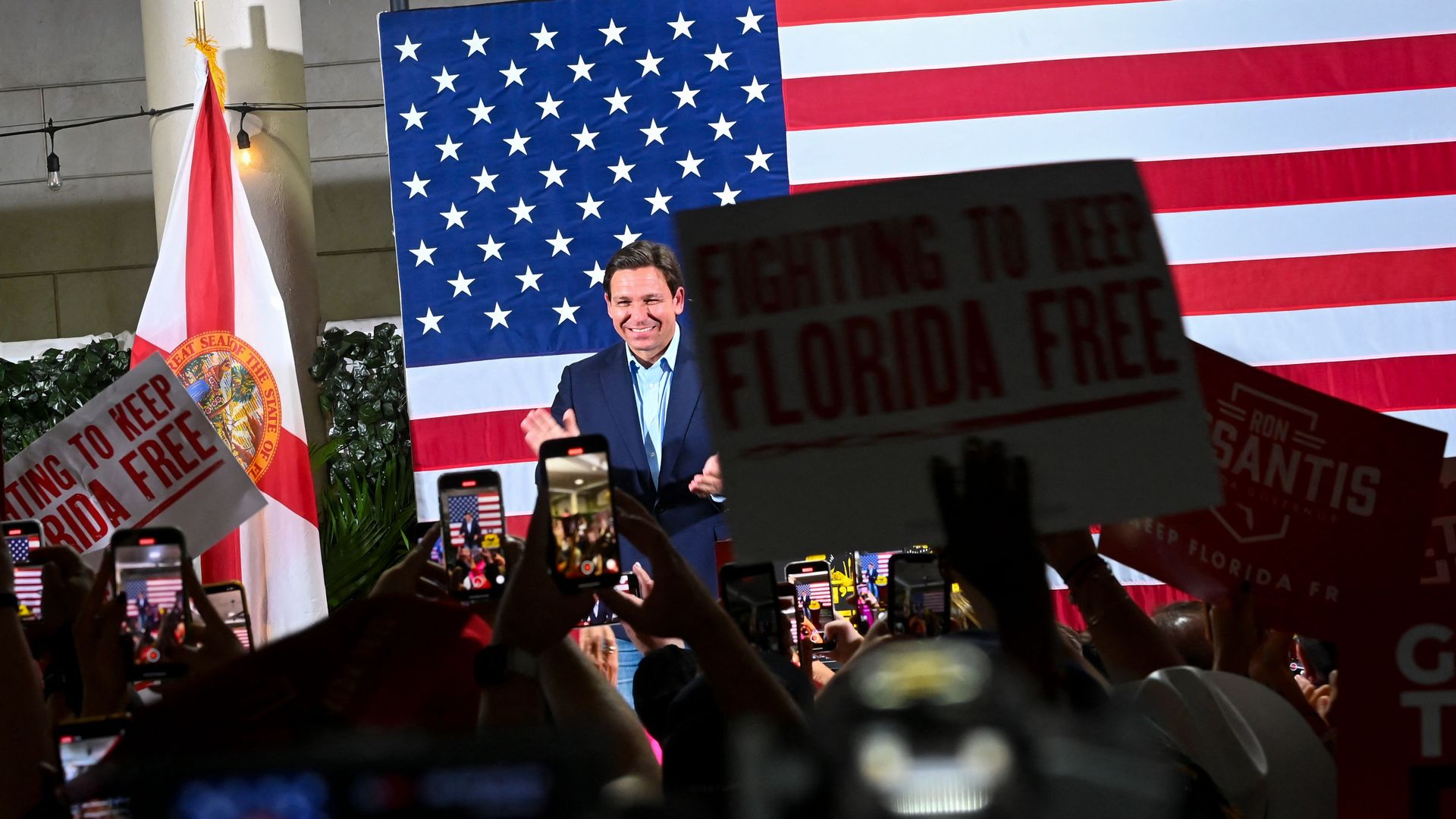 Florida Gov. Ron DeSantis smiles as a crowd of supporters cheers for him.