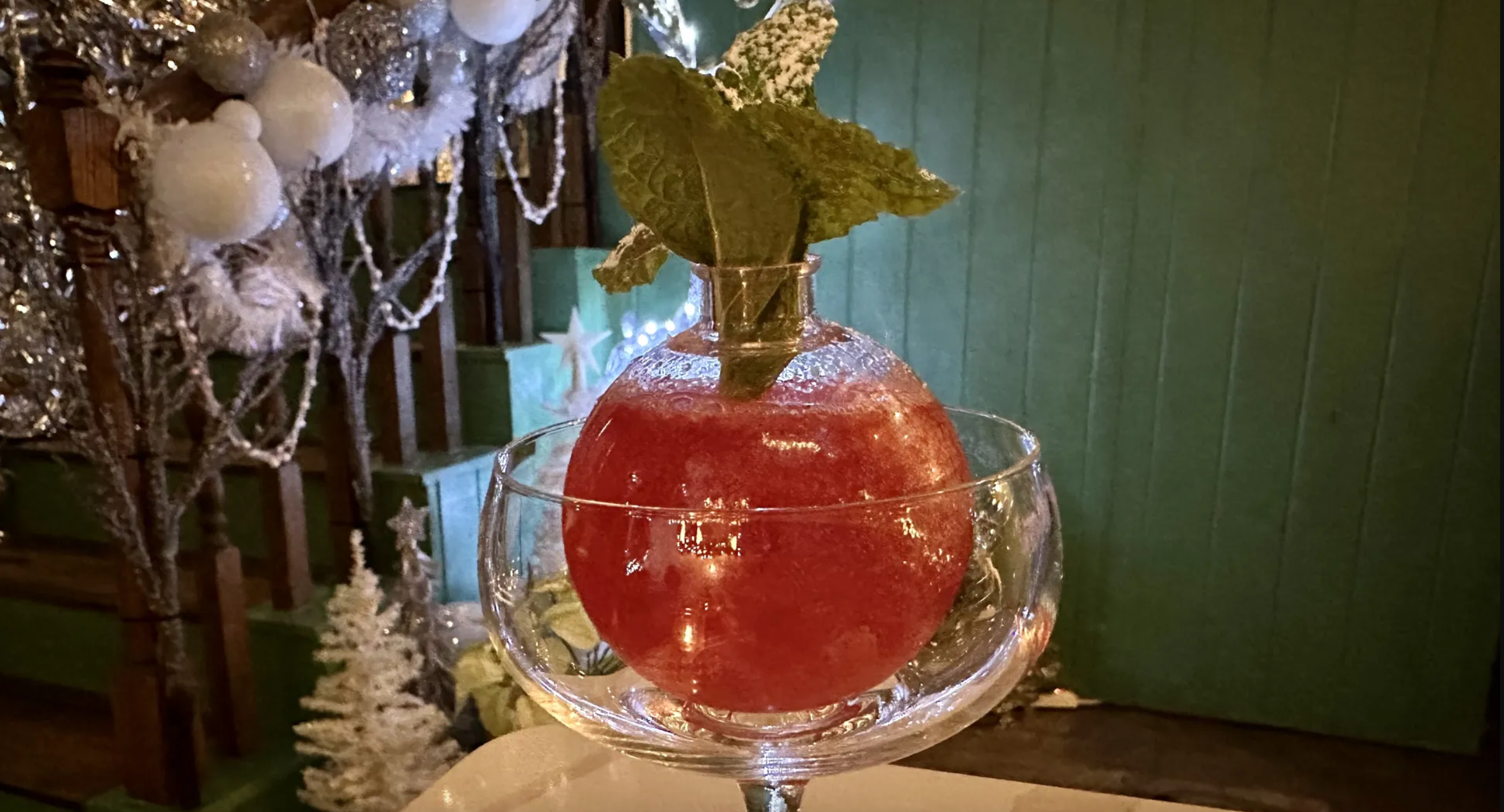 A photo of a glass holding a clear ornament with a red liquid inside 