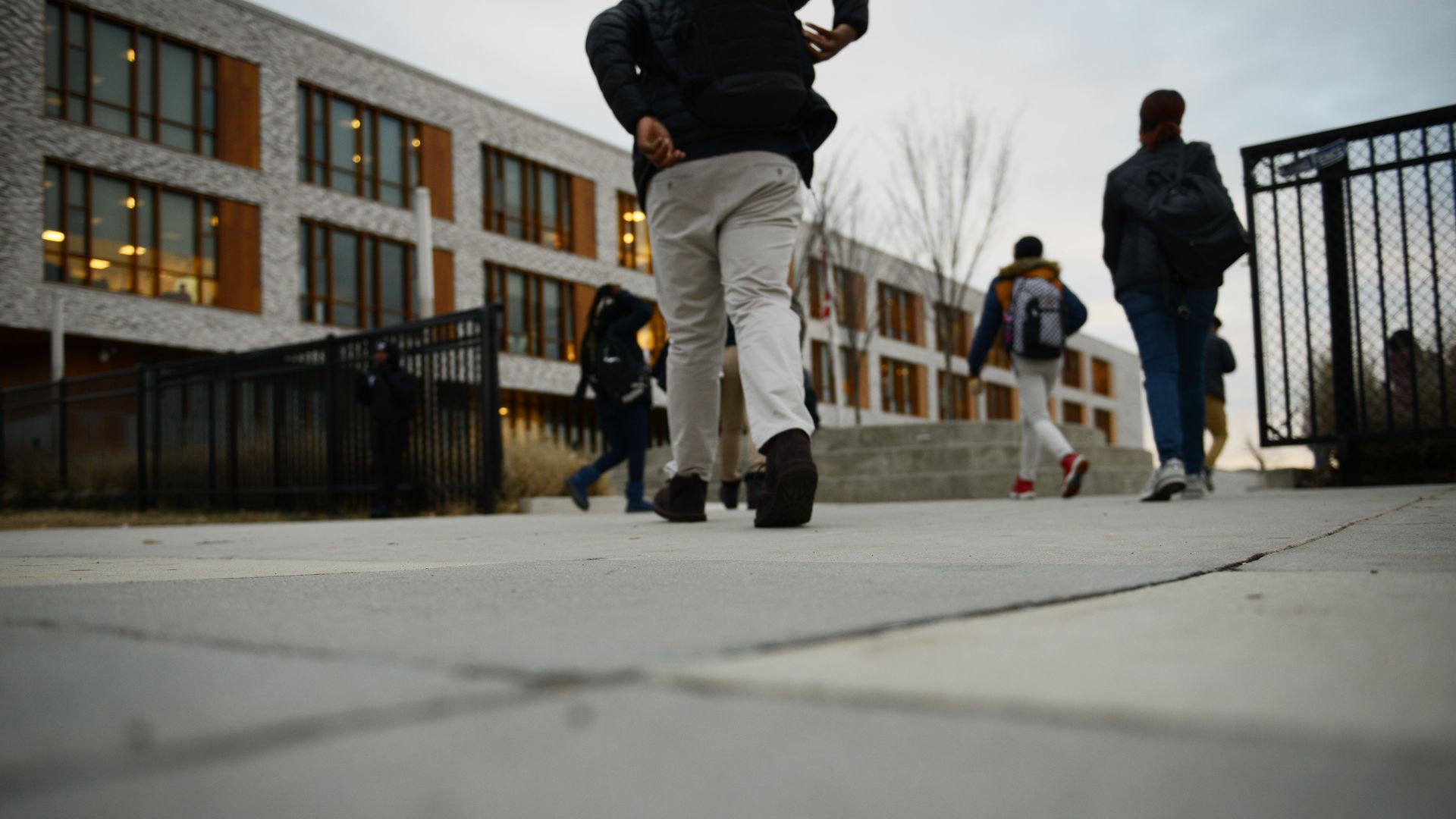 A ground view of students walking into a school building.