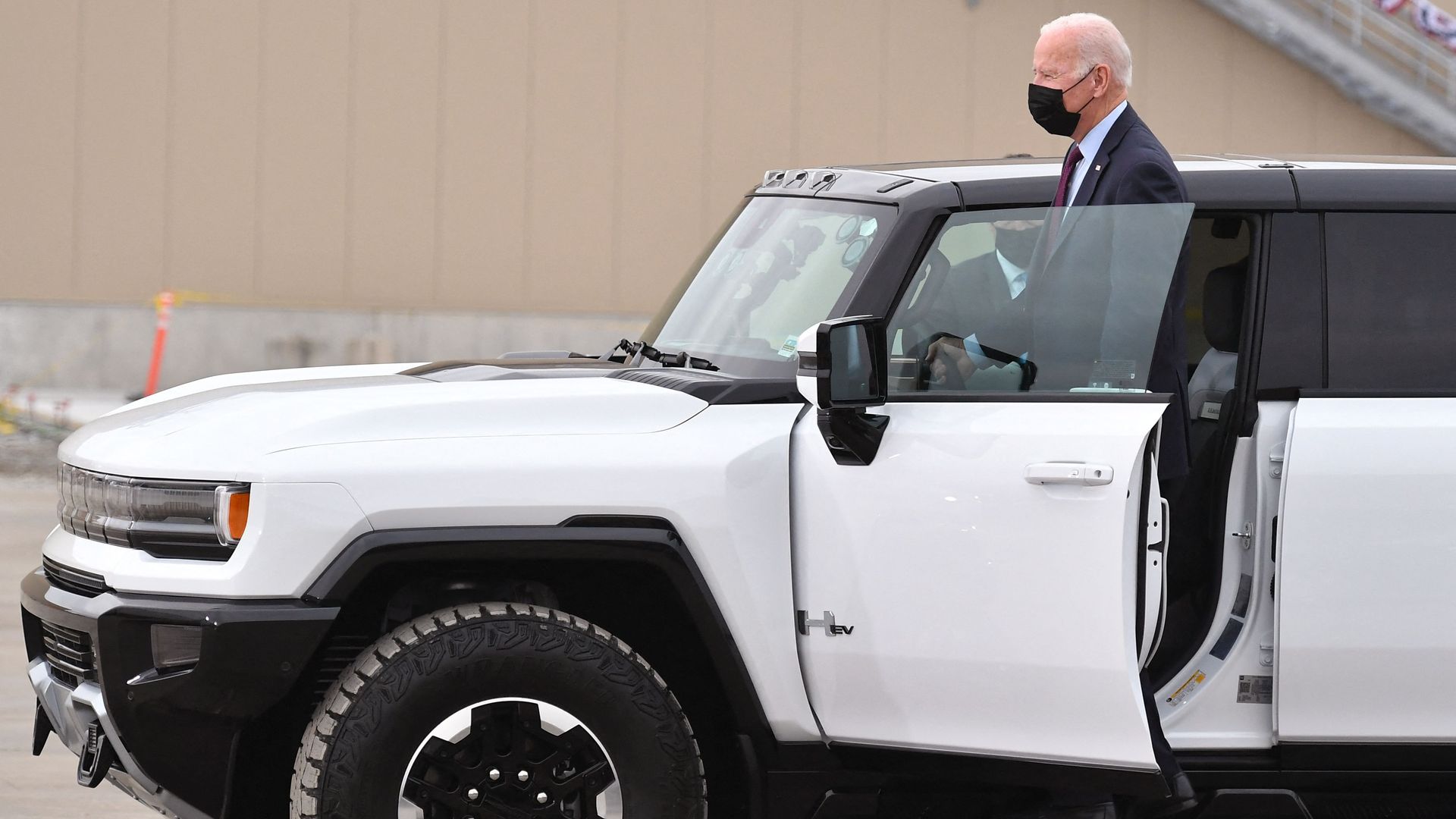President Biden is seen standing on the door sill of an electric Hummer while visiting at GM assembly plant in Michigan.