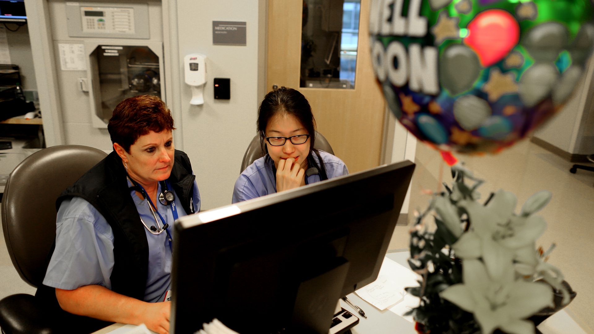 Surgical nurses look at a computer in a hospital.