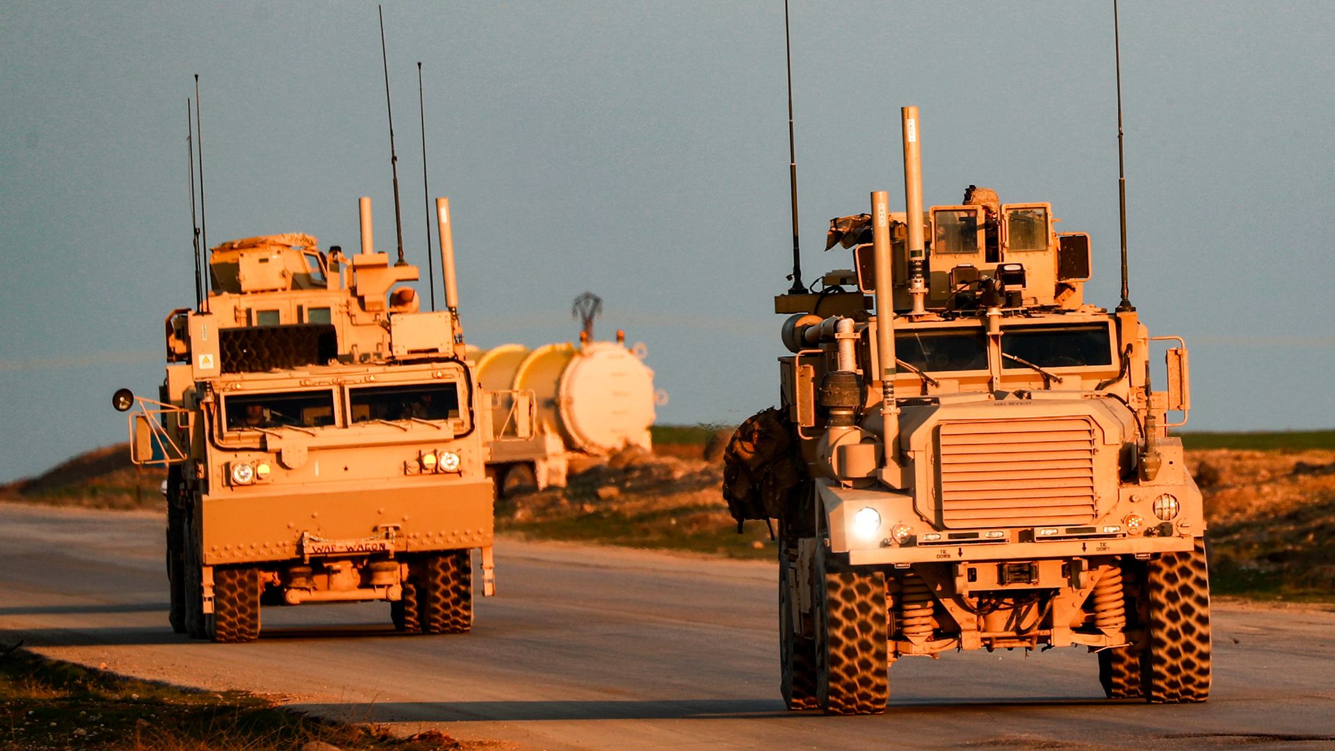 Marine Corps tactical vehicles drive along a road in Syria