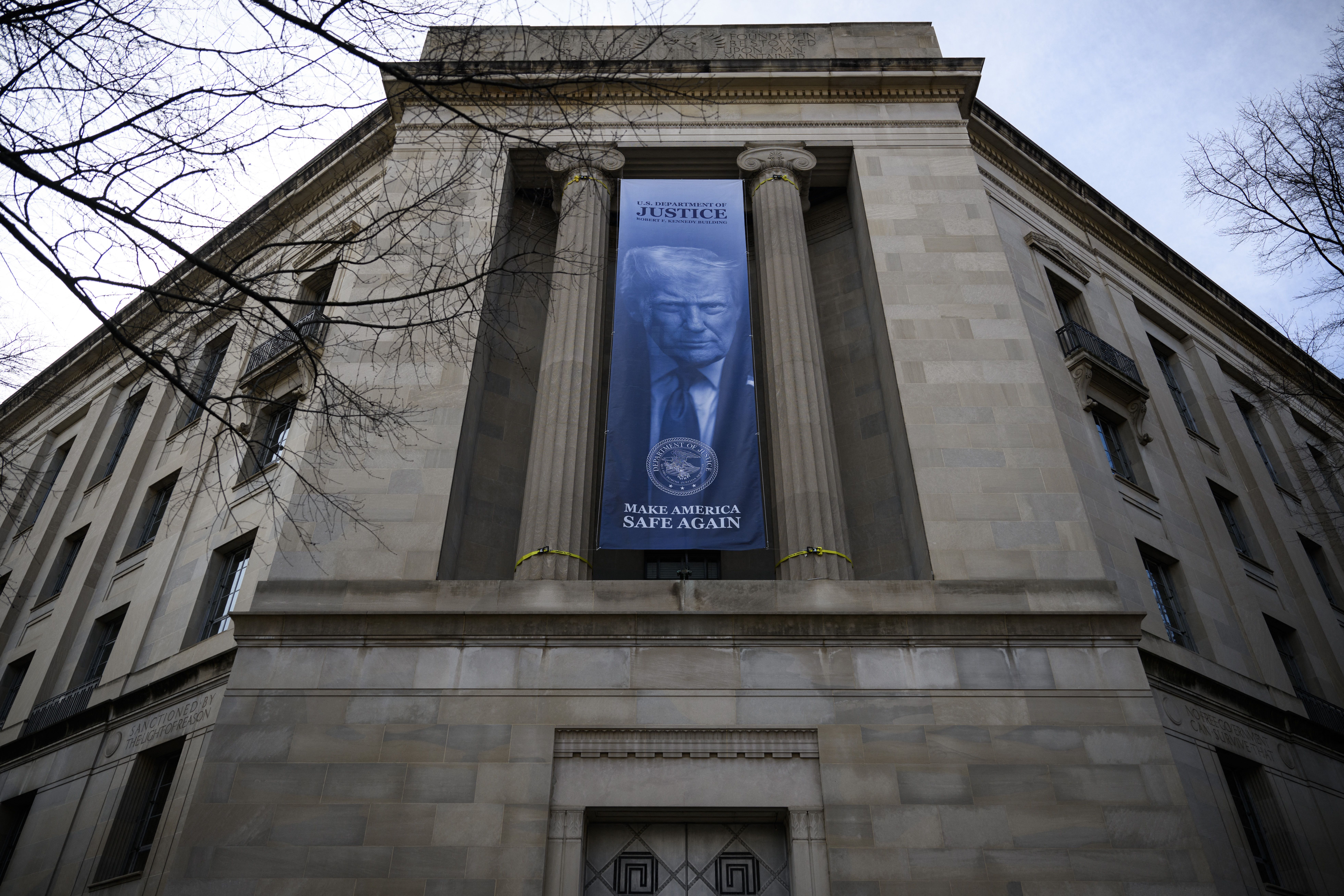 A new banner featuring an image of US President Donald Trump is displayed on the facade of the US Department of Justice headquarters, in Washington, DC, February 20, 2026. (Photo by Drew ANGERER / AFP via Getty Images)