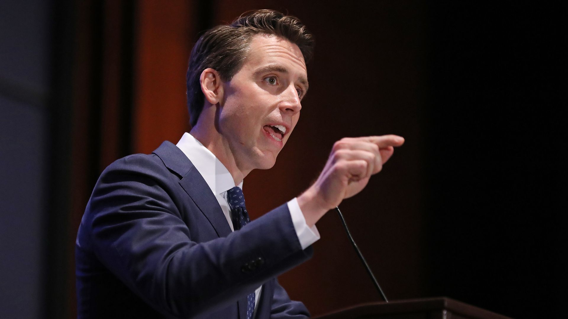  A photo of Sen. Josh Hawley pointing and speaking while standing at a podium.