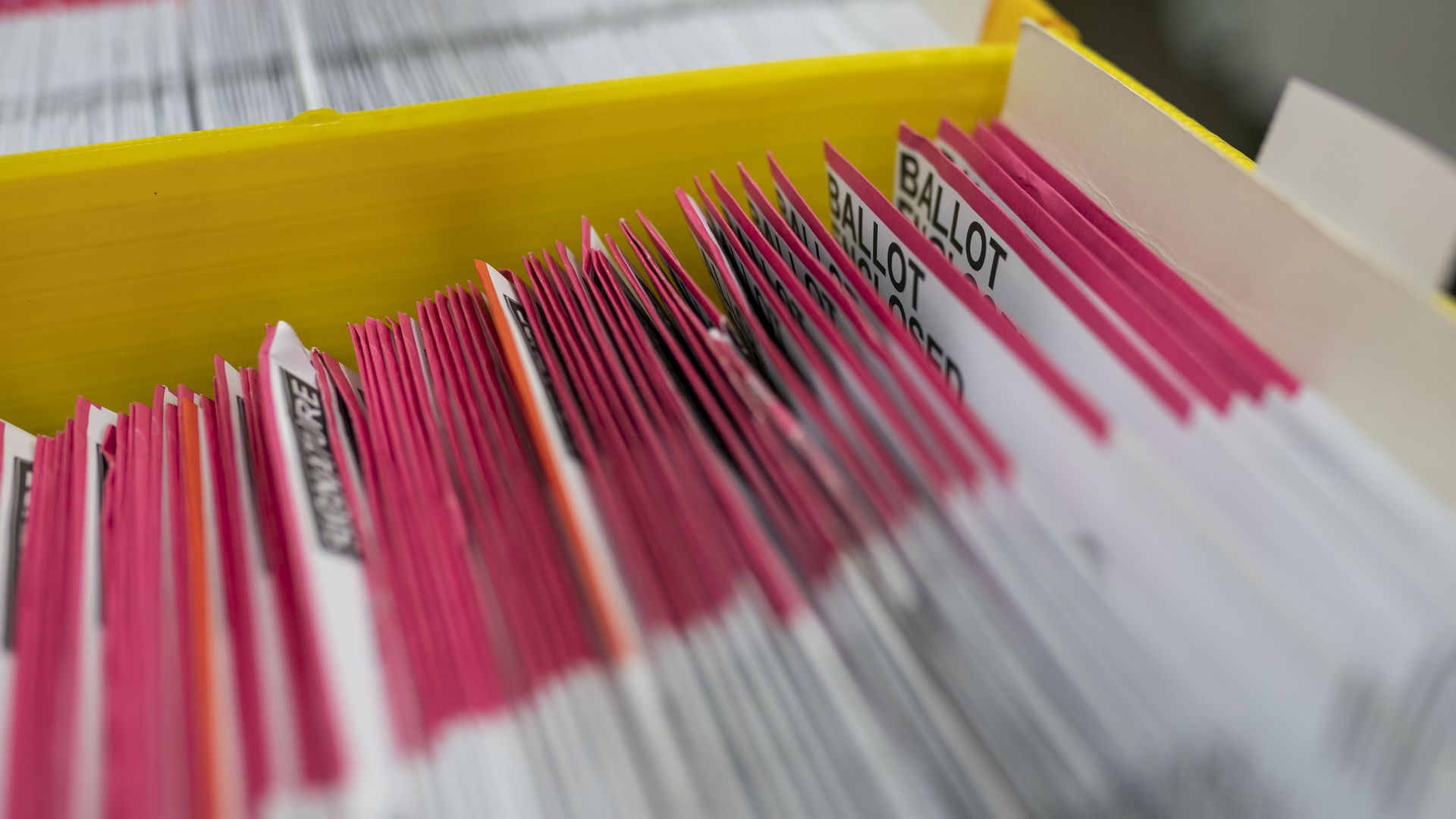 Dozens of ballots are seen in a box.