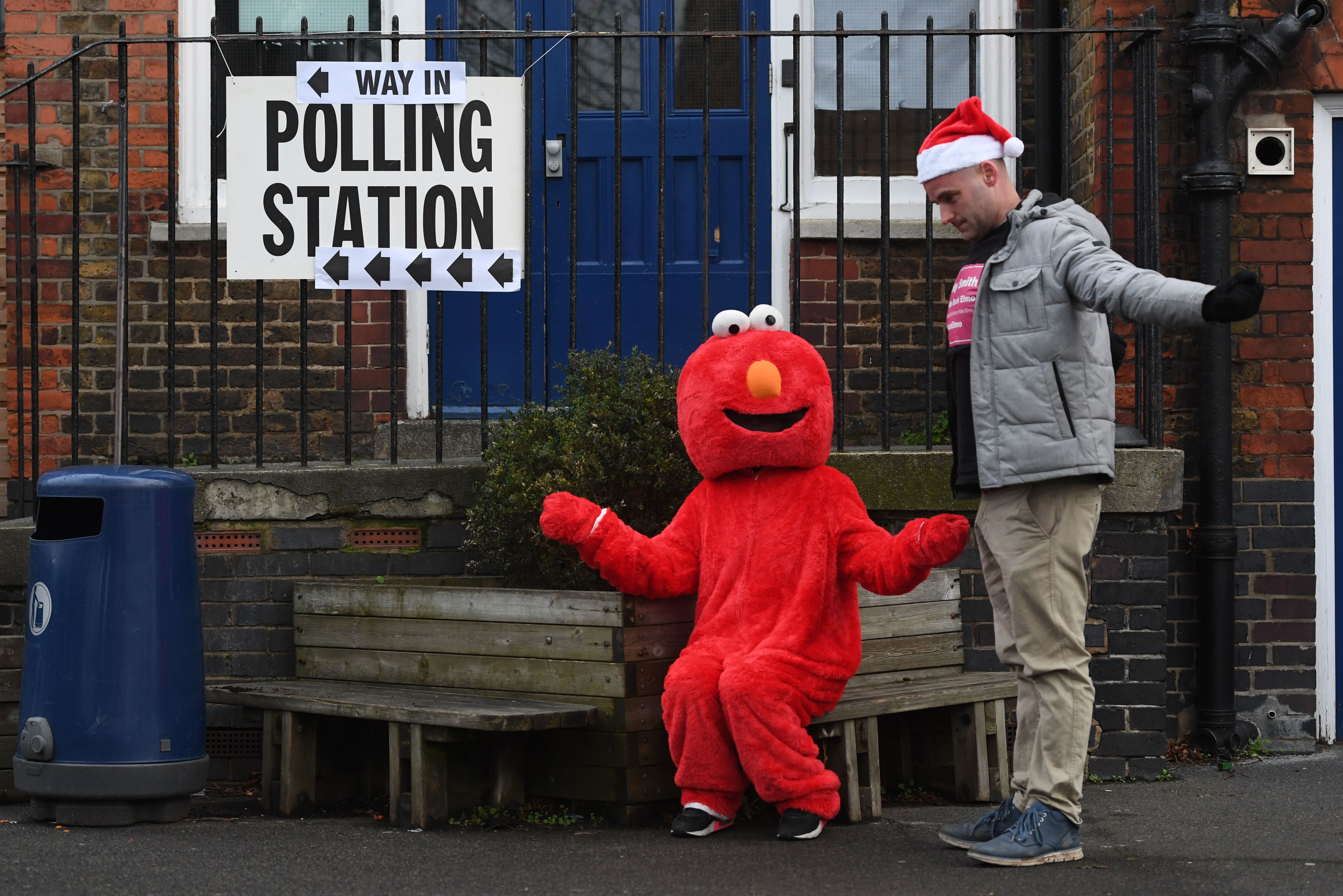 A man in a santa hat and a man in an Elmo costume outside the polling station at Pakeman Primary School in Islington, north London