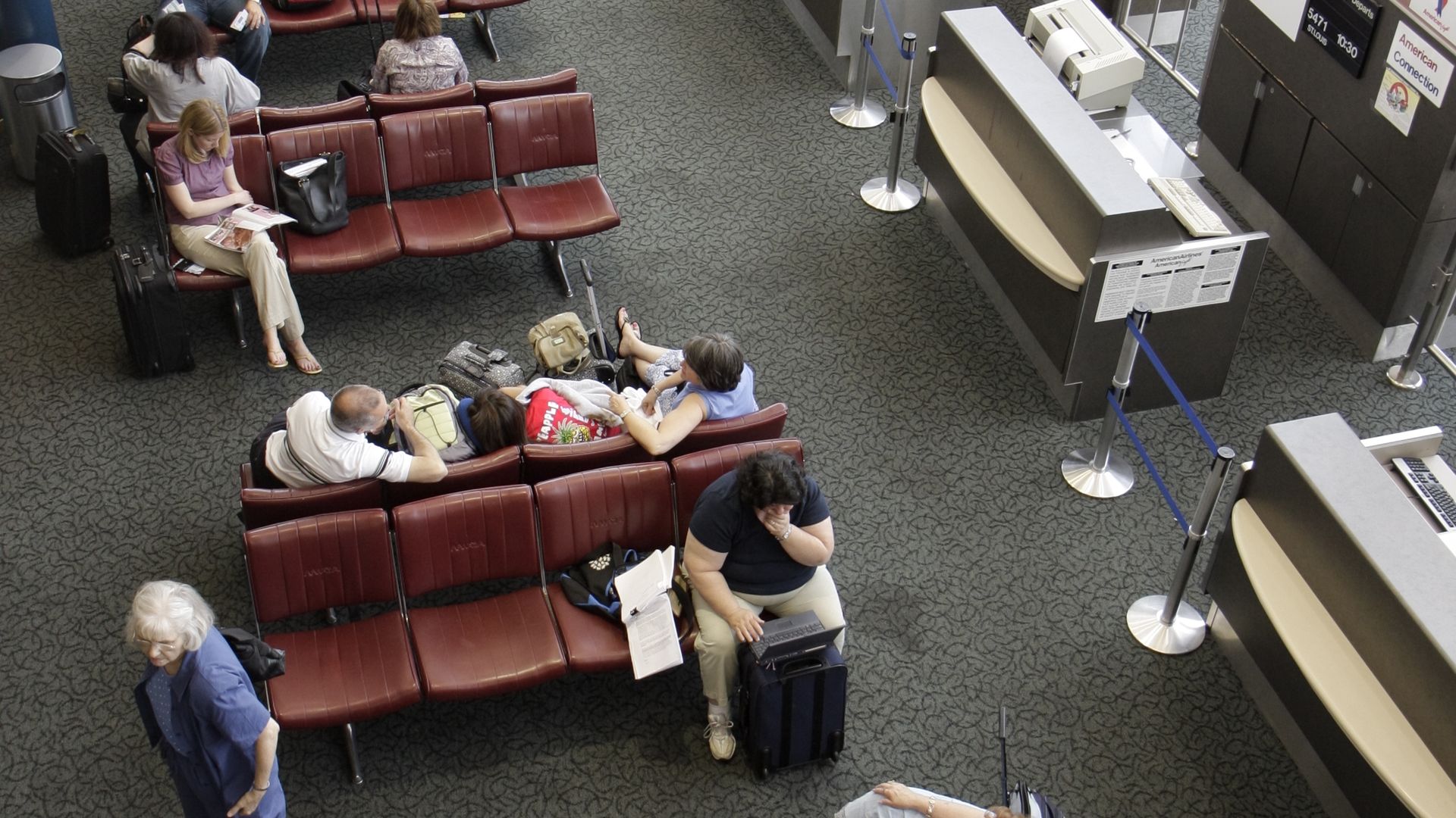 A photo of people waiting at an airport terminal.