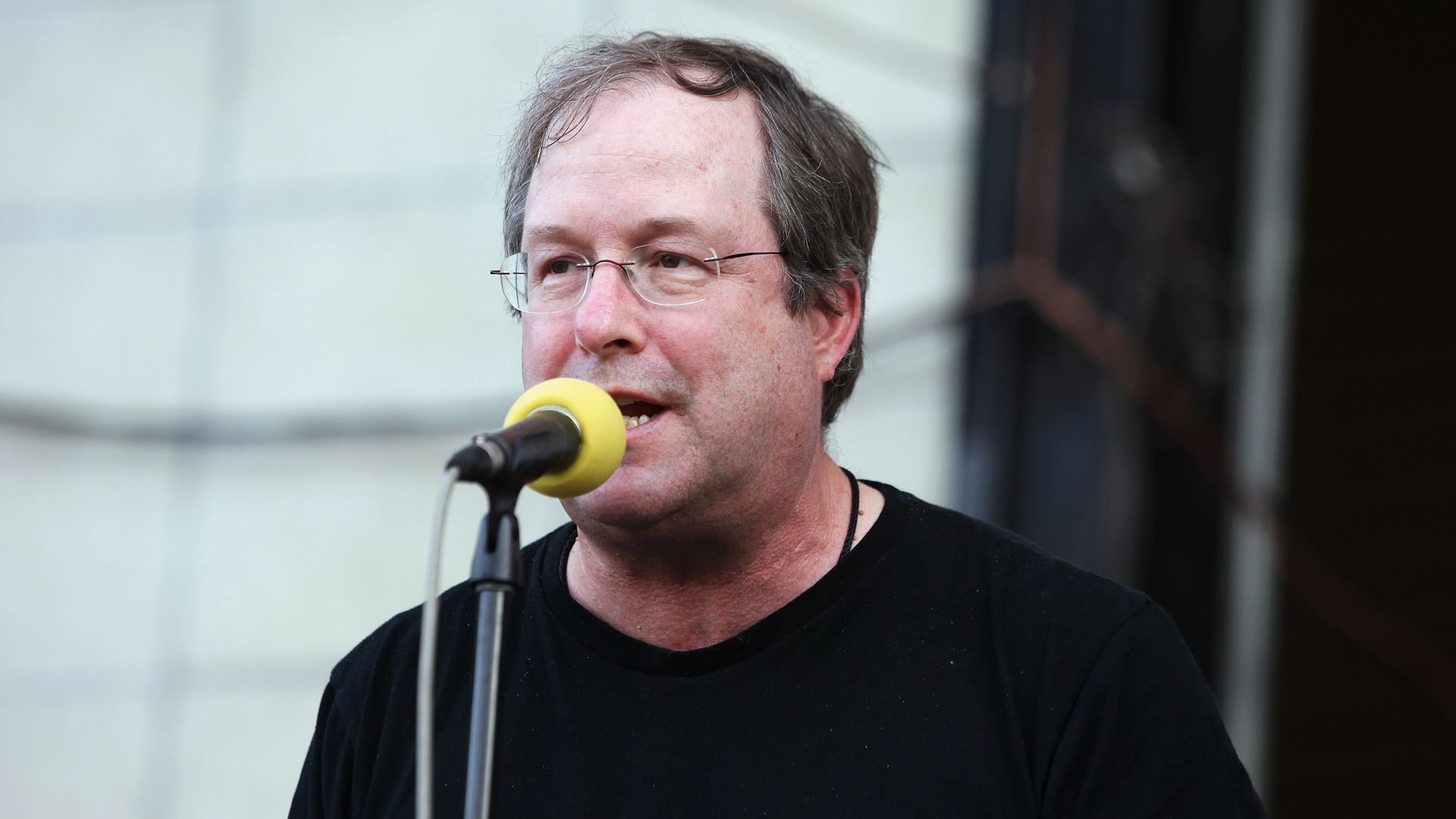 Photo of man on microphone on a stage. 