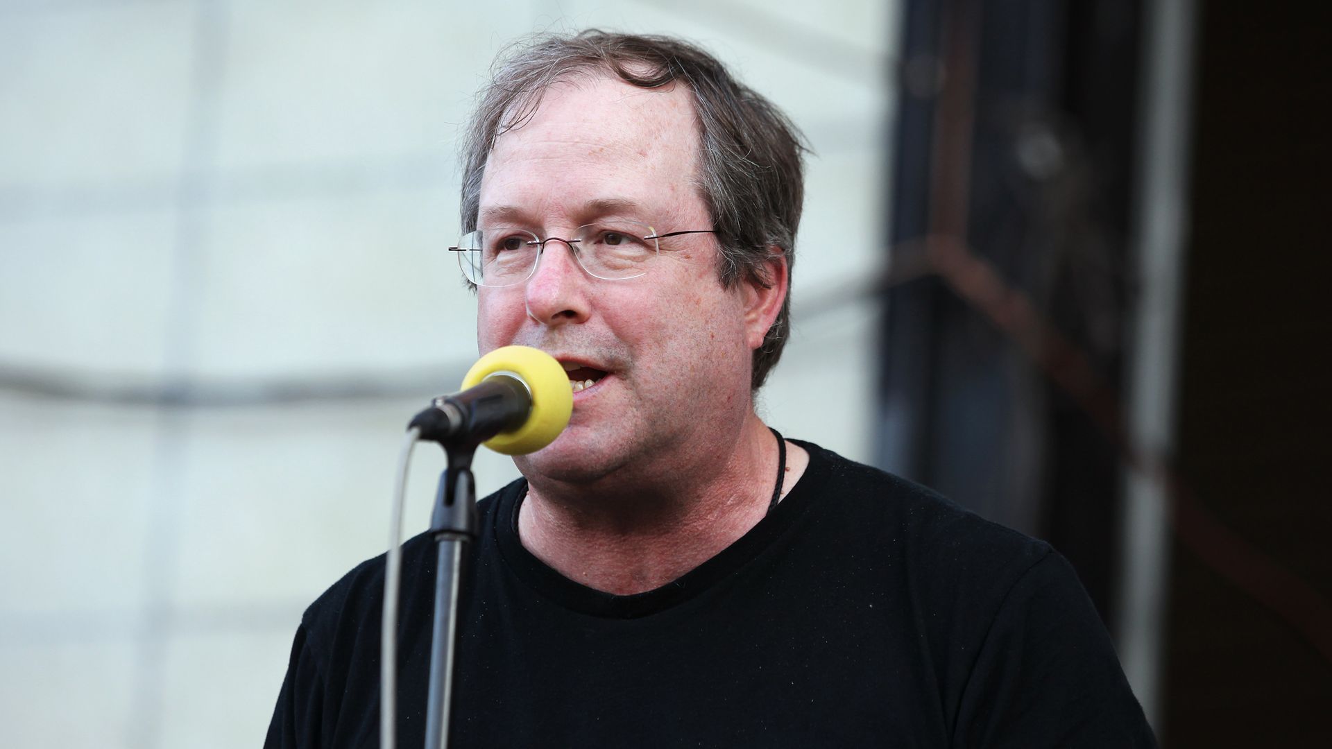 Photo of man on microphone on a stage.