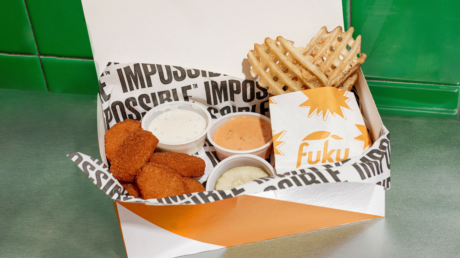 A box with chicken nuggets, waffle fries and sauces