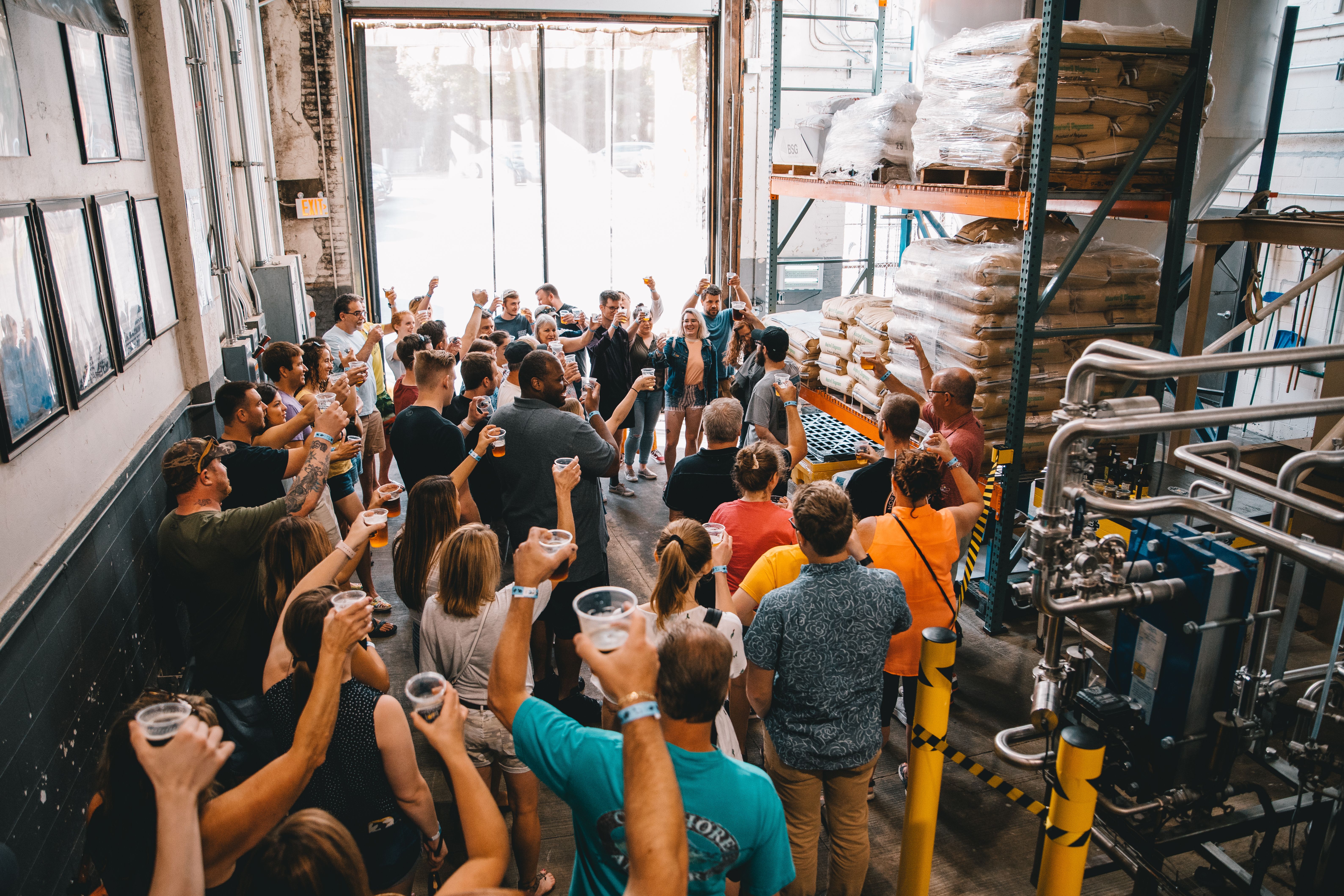 people hold up cups of beer