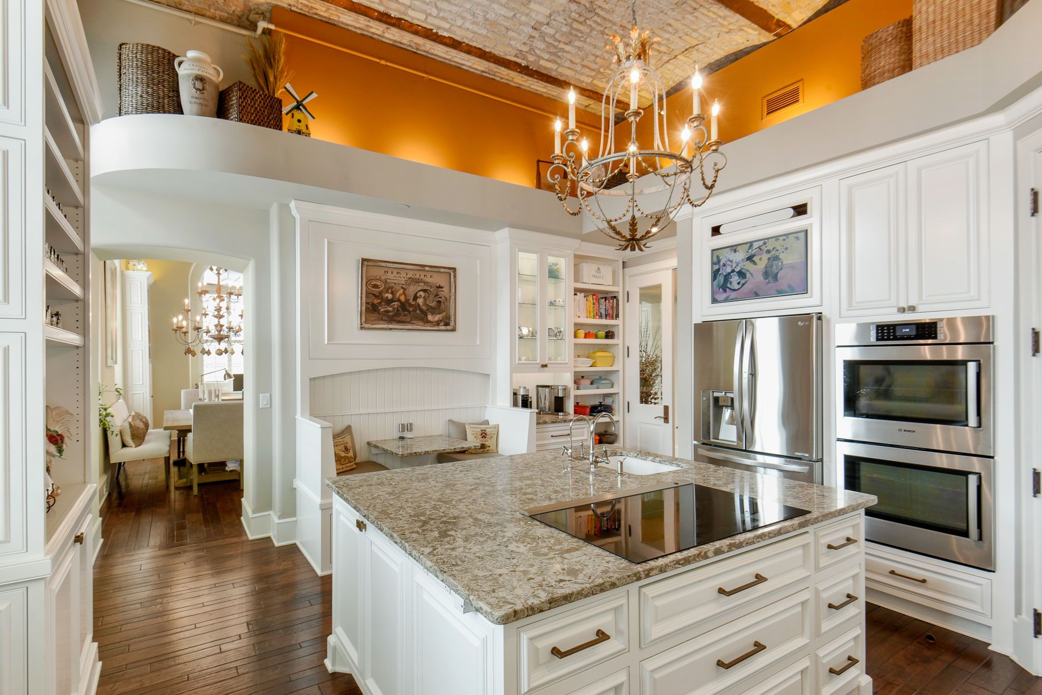 A photo of a kitchen with orange walls and white cabinets.