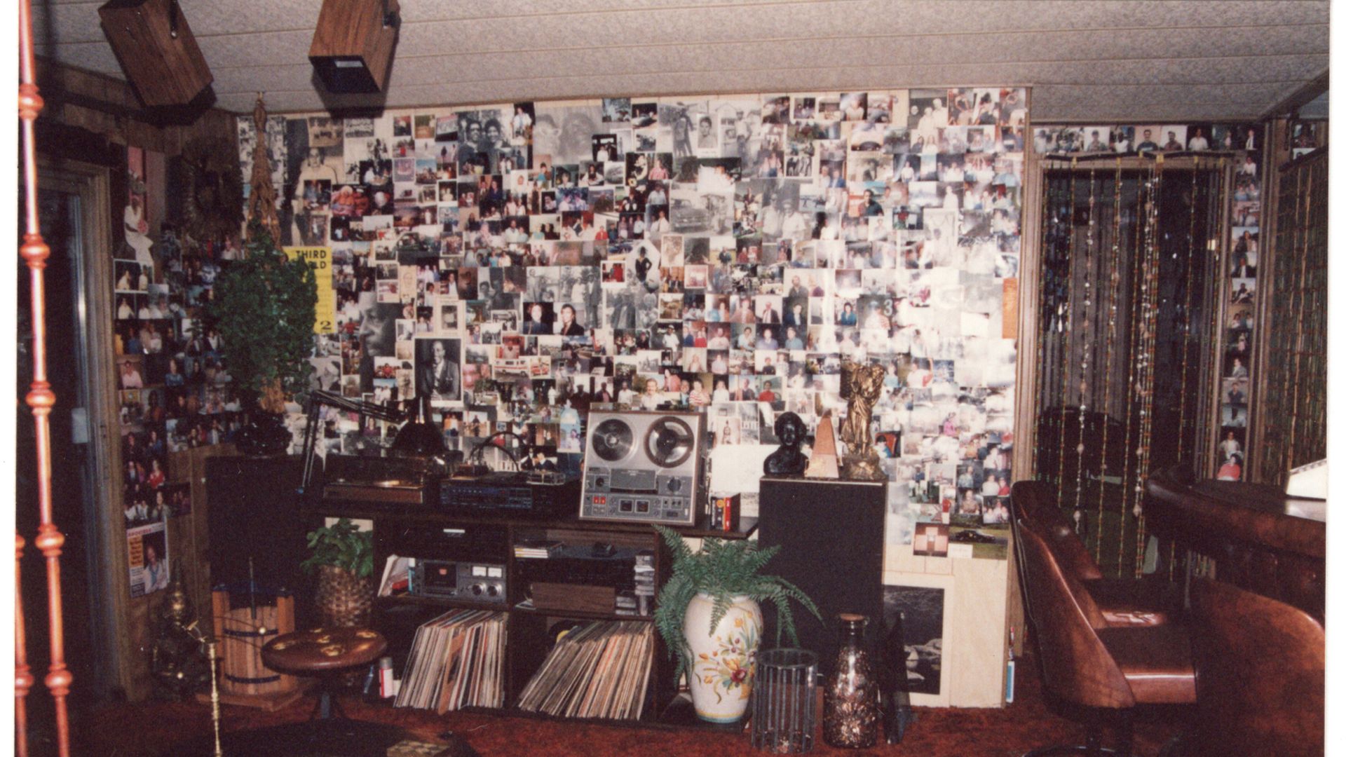 A room with vinyl LPs hi-fi equipment a reel-to-reel tape player and a wall of photographs of musicians