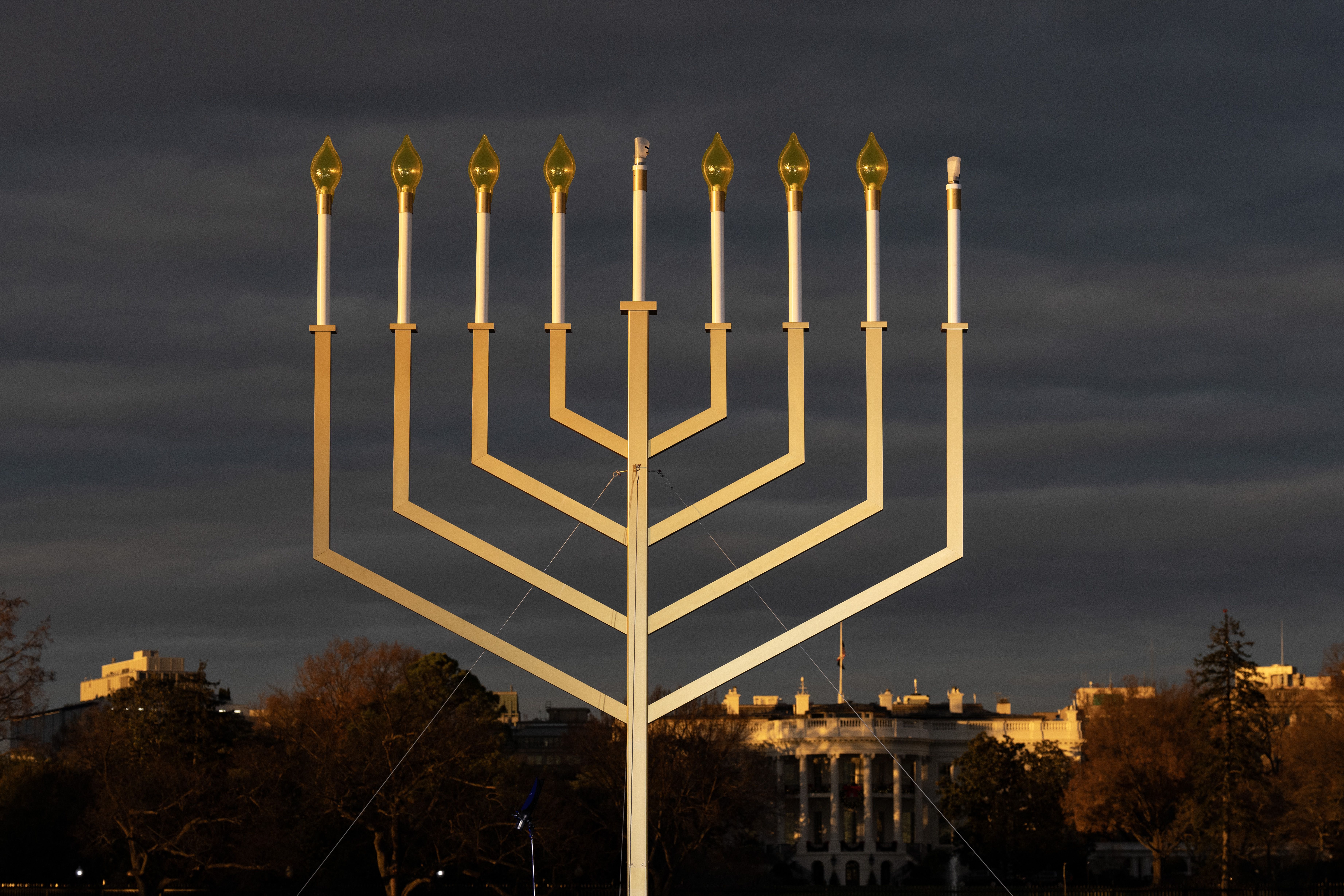 The National Menorah against a darkened sky with the White House in the background 