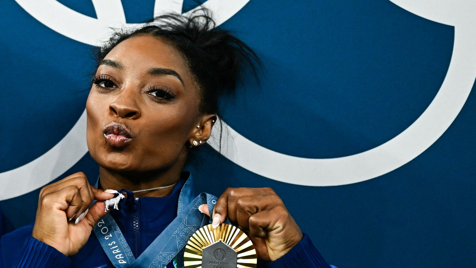 Simone Biles poses with her gold medal and a goat necklace after the podium ceremony for the artistic gymnastics women's all around final of the Paris 2024 Olympic Games at the Bercy Arena in Paris, on August 1,