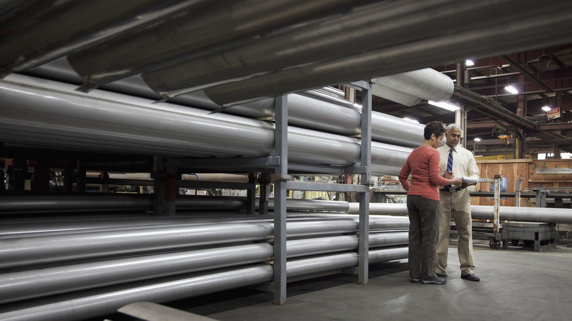 A man and lady talking near large metal pipes