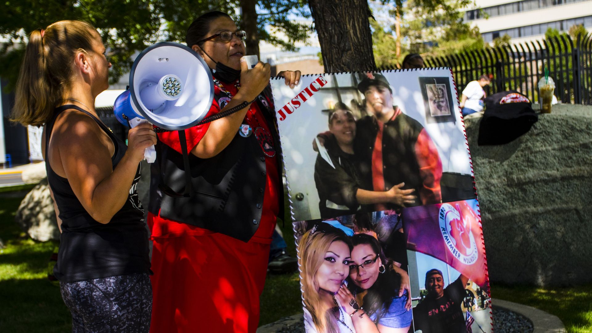 A protester speaks into a bull horn while holding a sign with images of deceased native American woman Georgianna Jackson during the protest.