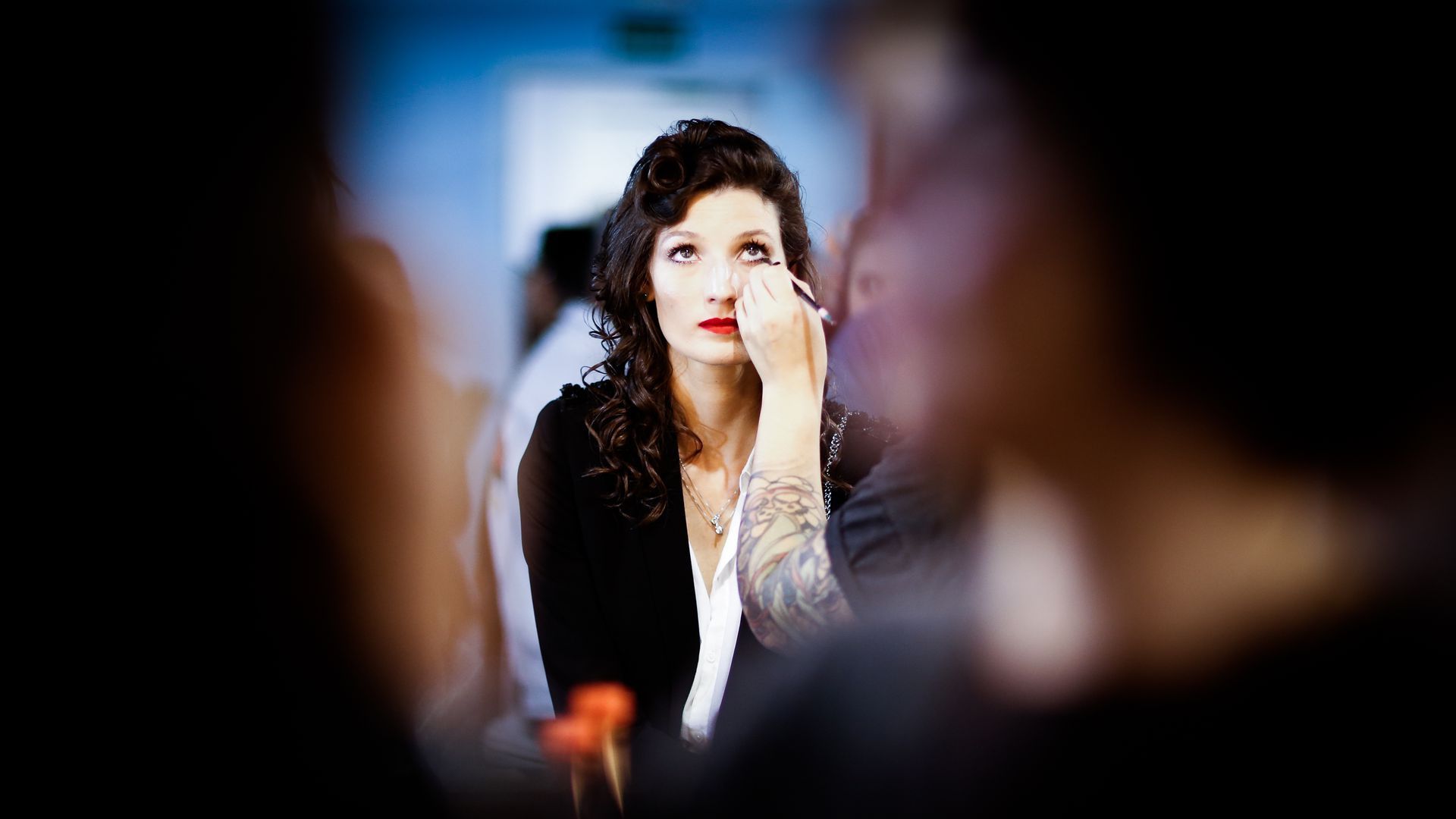 Woman using eye liner at a beauty counter.