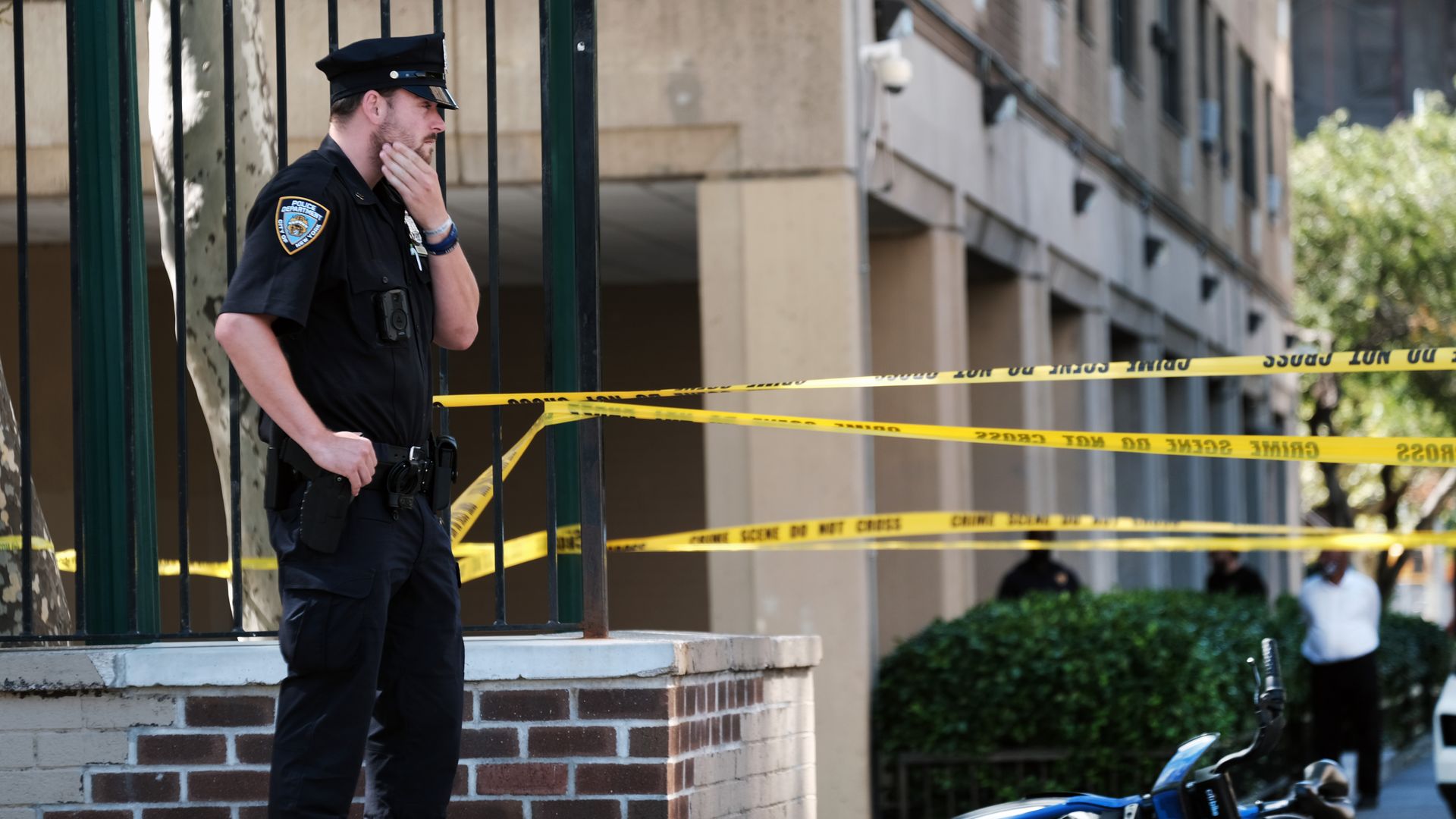 A Citi Bike sits at the scene of a shooting with yellow tape in Manhattan as a officer looks.