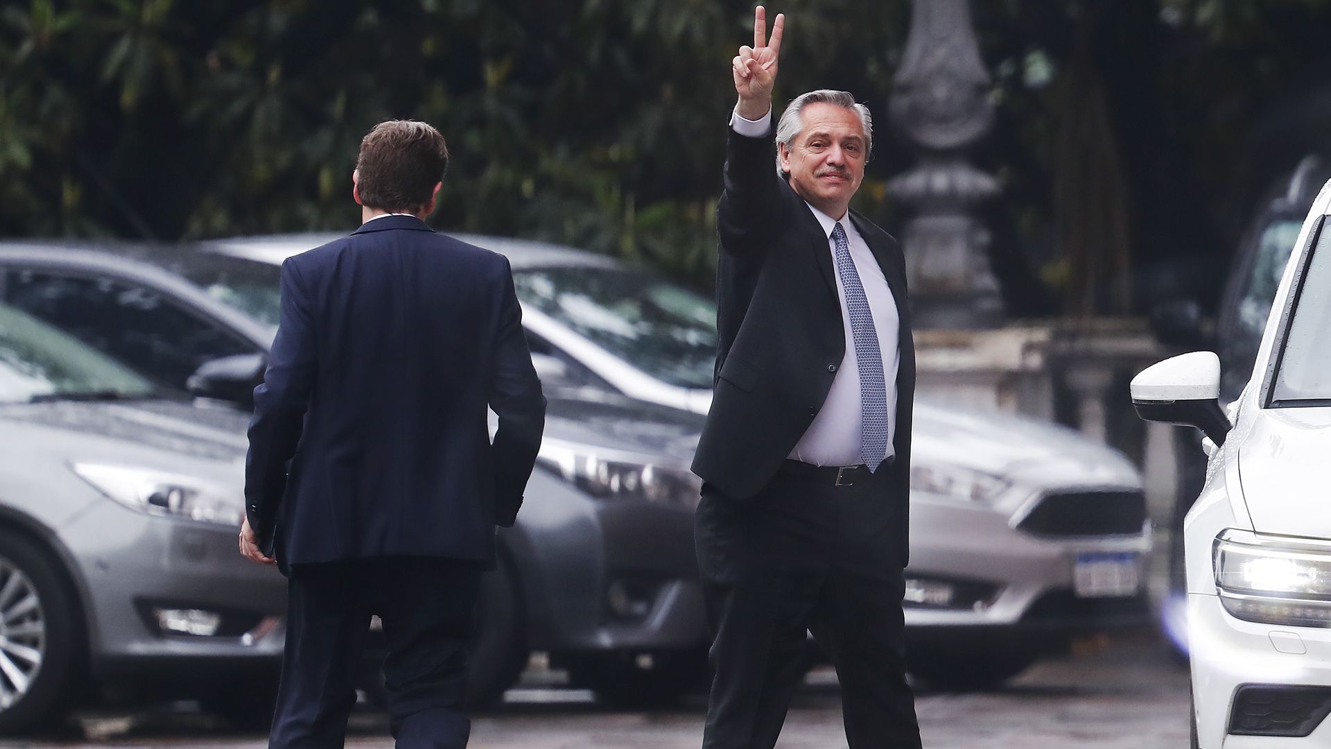 Alberto Fernandez waves while walking to a car