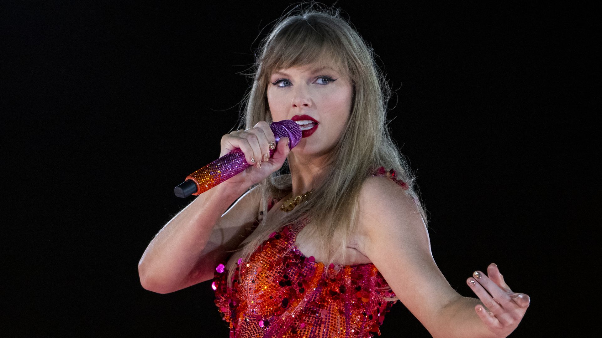 Photo shows Taylor Swift in a red sequin outfit on stage.
