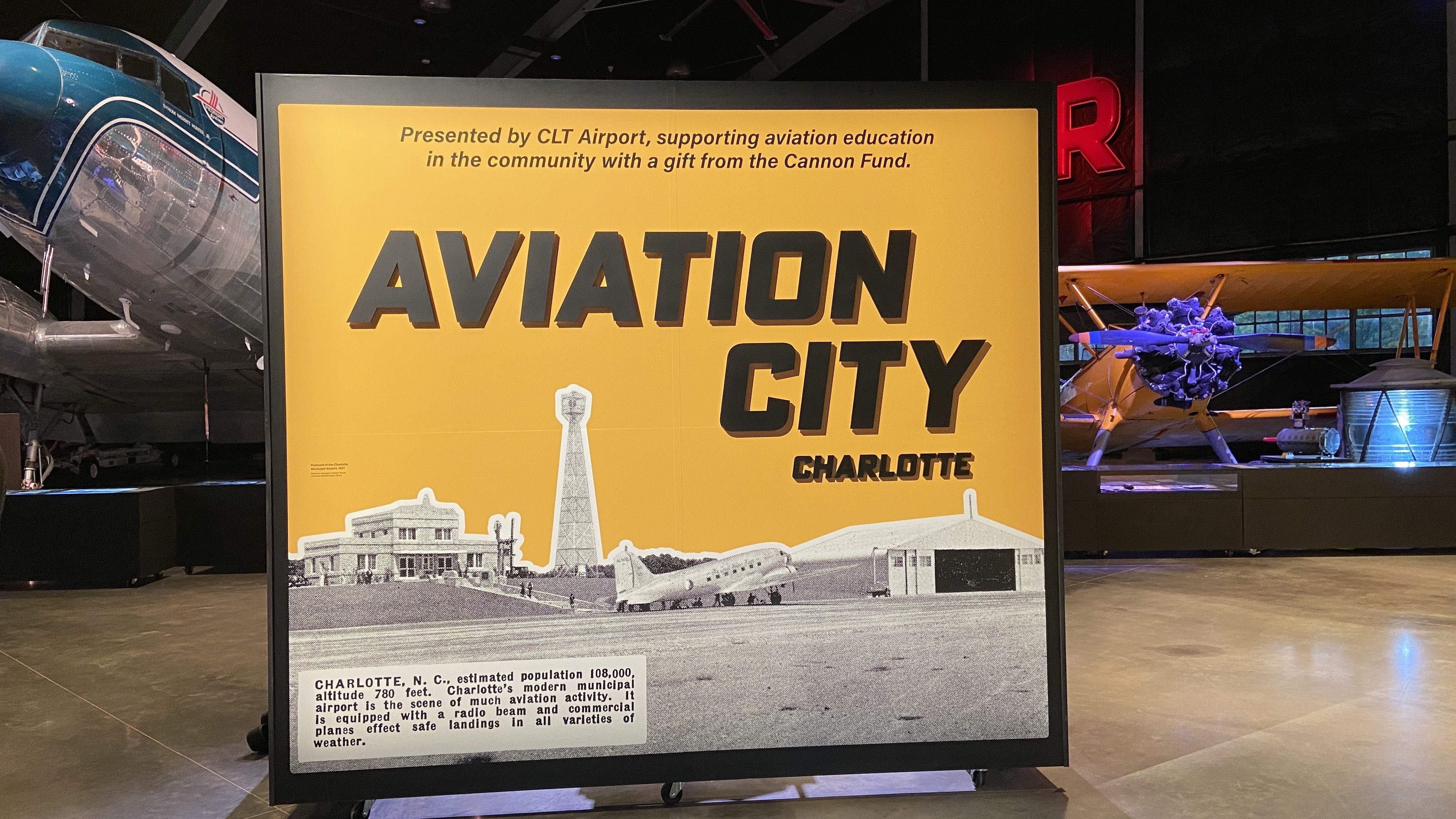 "Aviation City" on a yellow board with planes behind it.