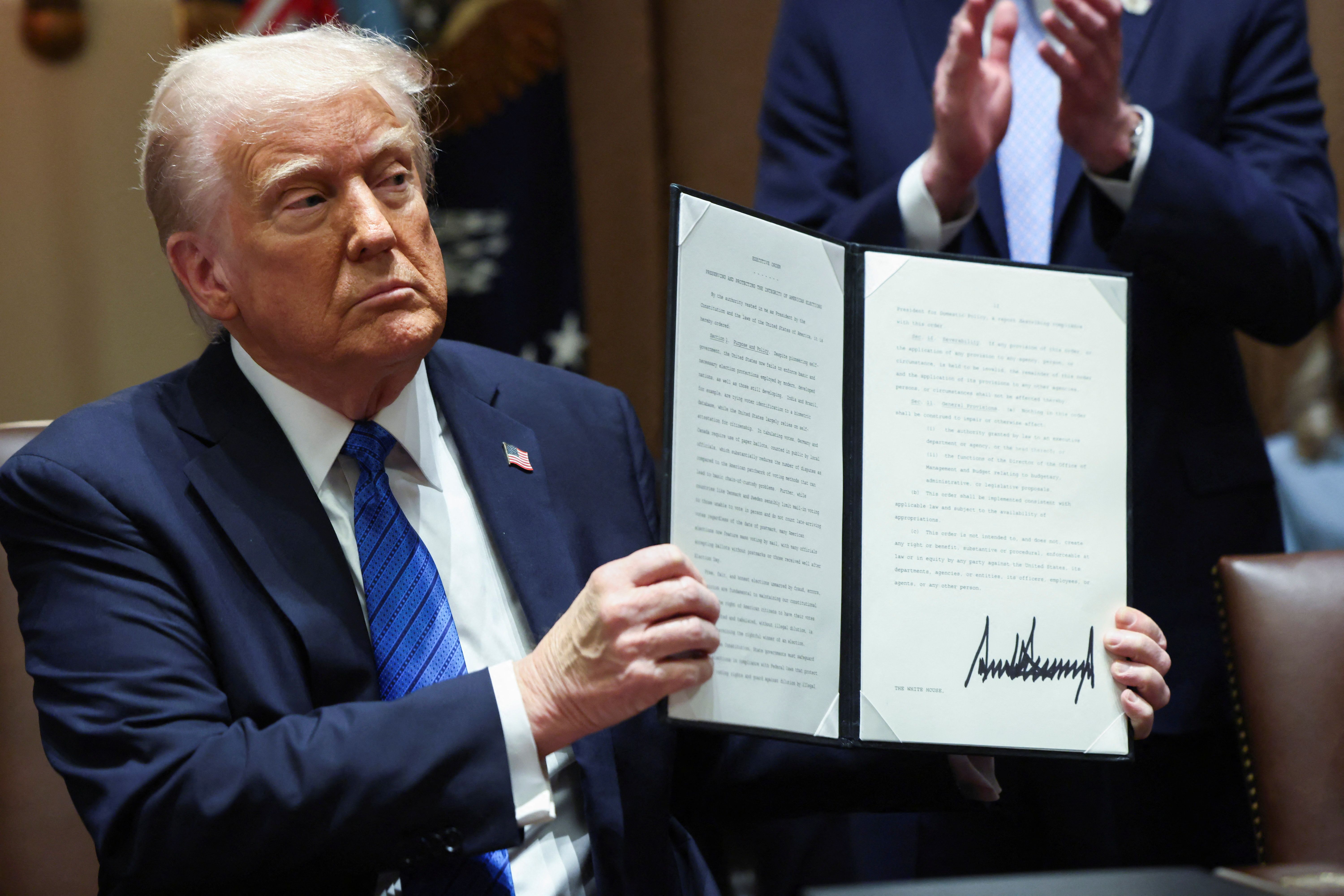 President Trump holds an executive order during a meeting with ambassador nominees in the Cabinet Room yesterday.