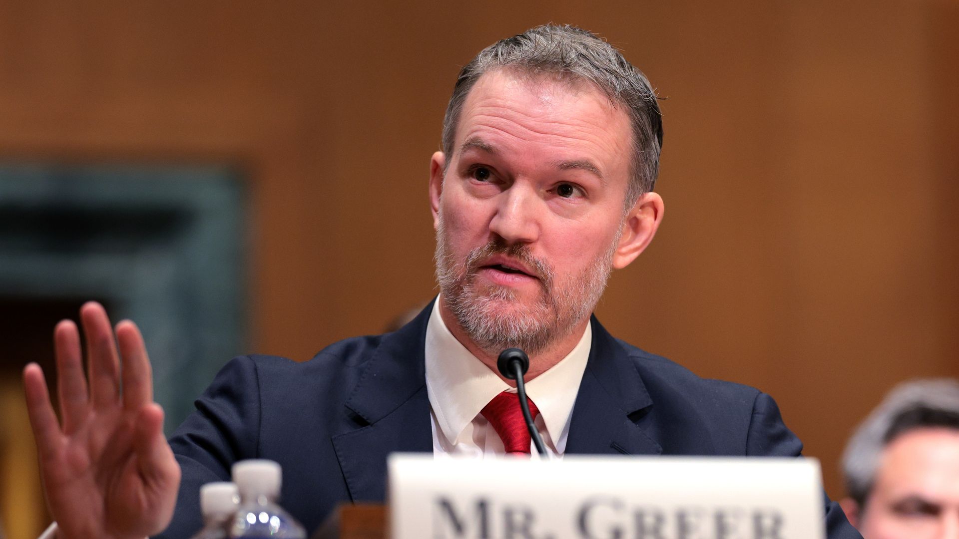 A person in a suit gestures with their hand