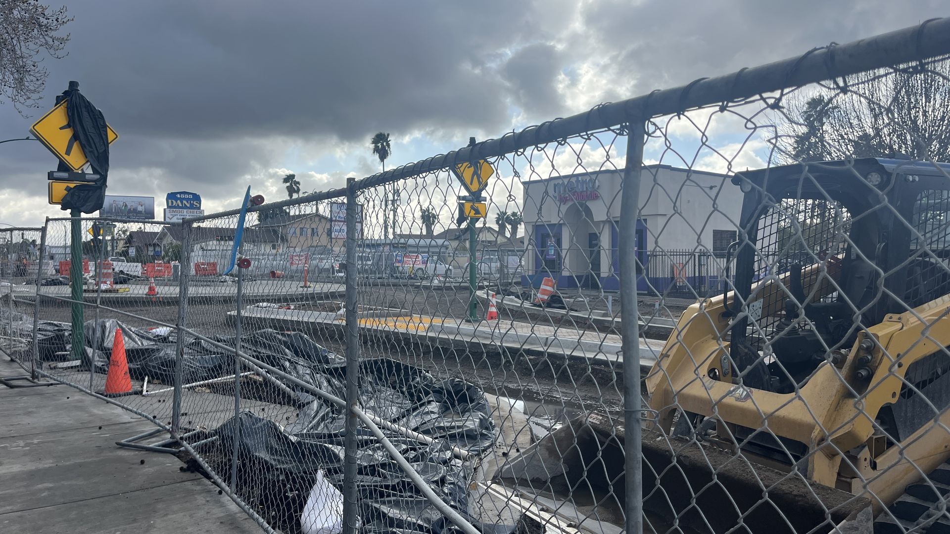 Construction machinery, materials and fencing barricade businesses along a torn up road.