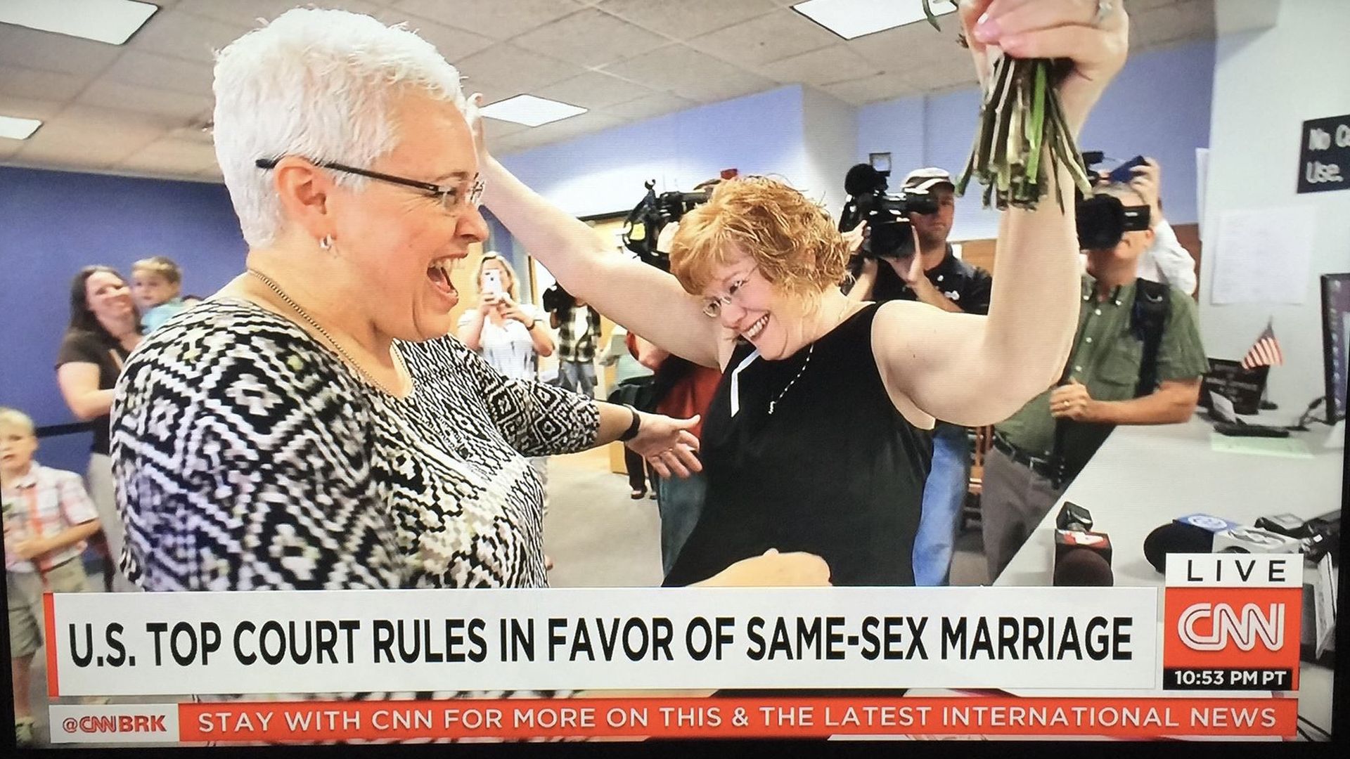 Mindy and Jimmie Beall receiving a marriage license 10 years ago inside the Franklin County Courthouse — a photo that was shared on CNN. The caption from the TV reads "U.S. Top Court Rules in Favor of Same-Sex Marriage."
