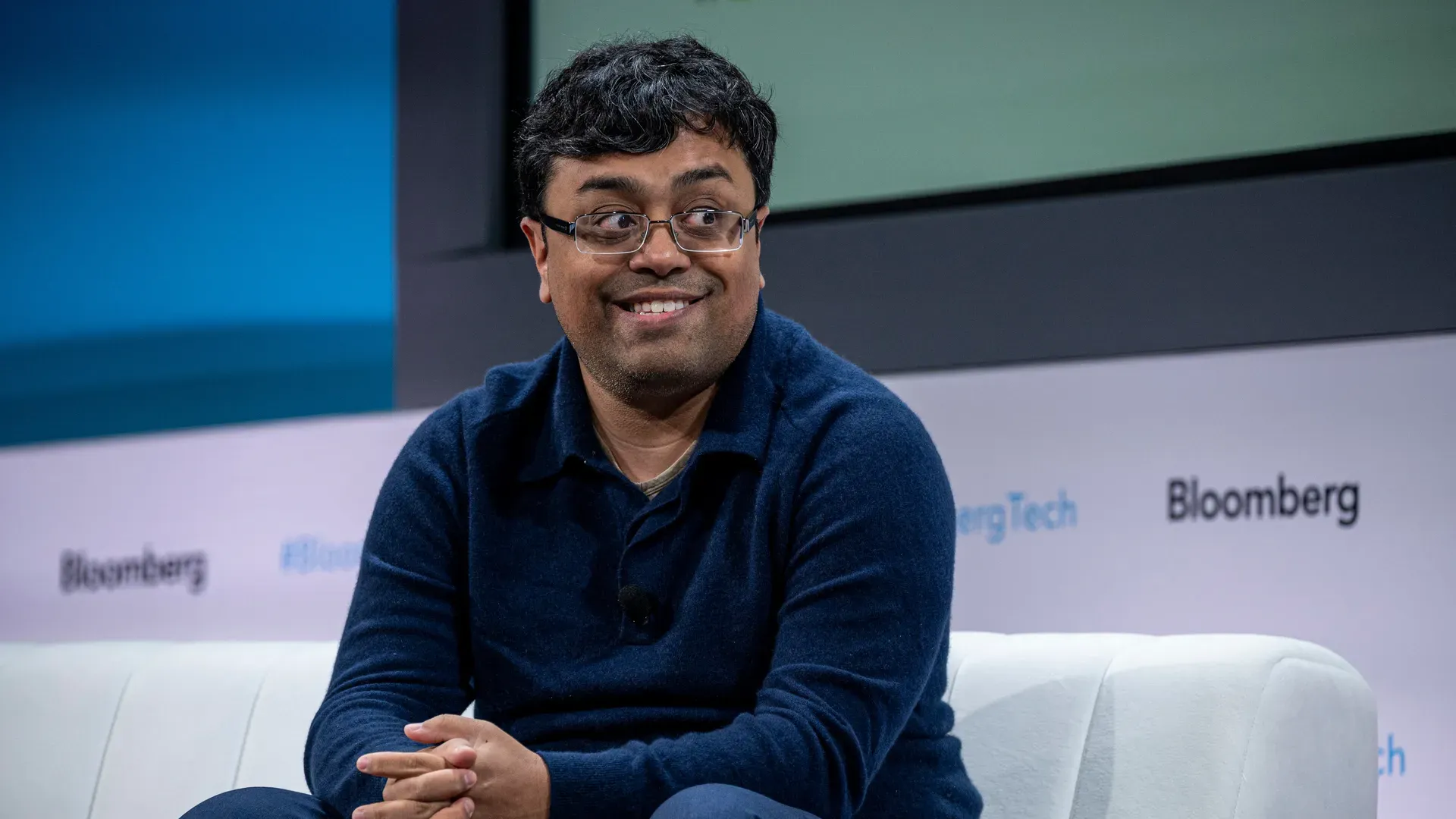 Emad Mostaque, founder of Stability AI Ltd. sitting on a white couch on a stage
