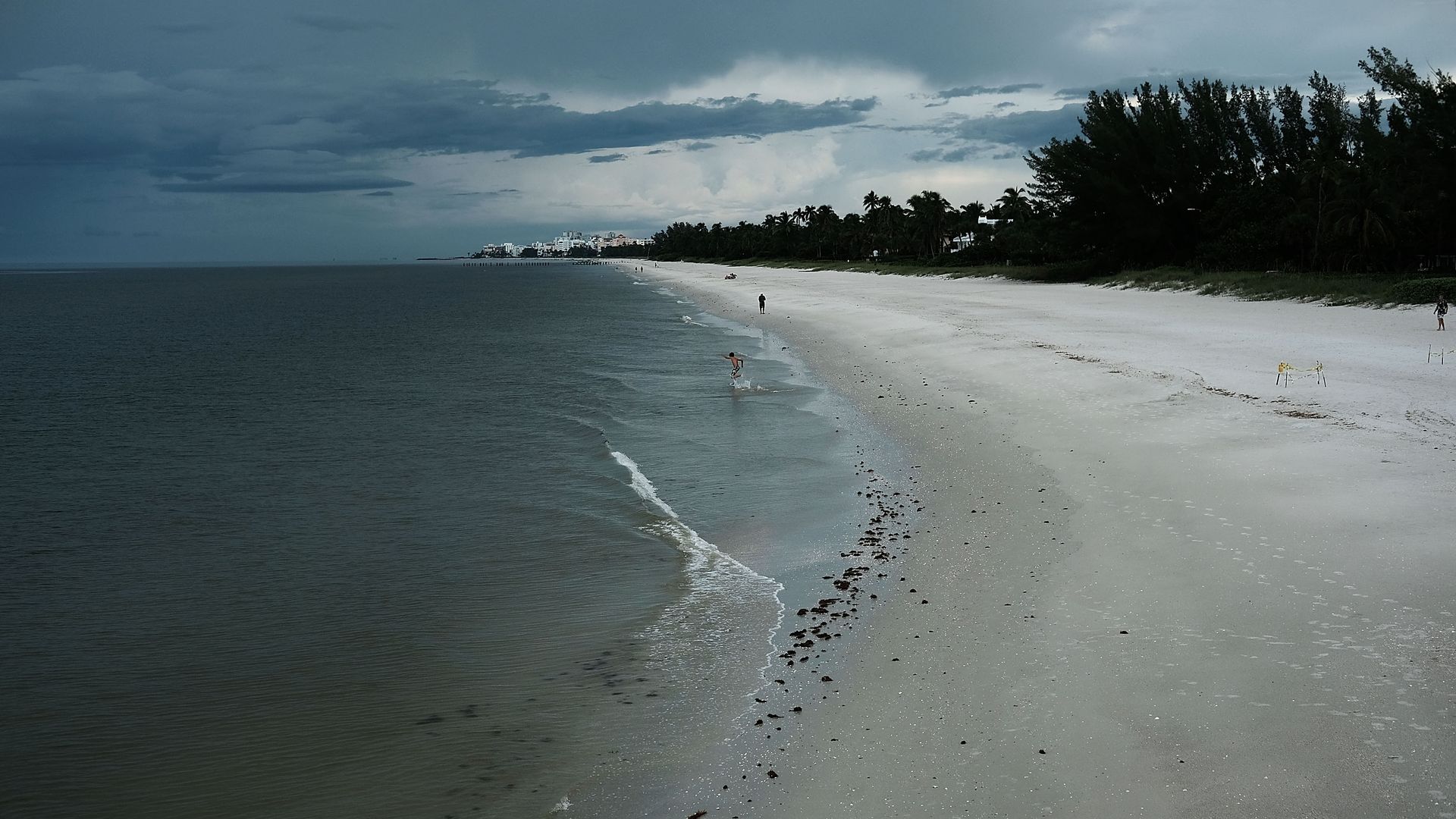 People walk on an empty beach in Naples, Florida.