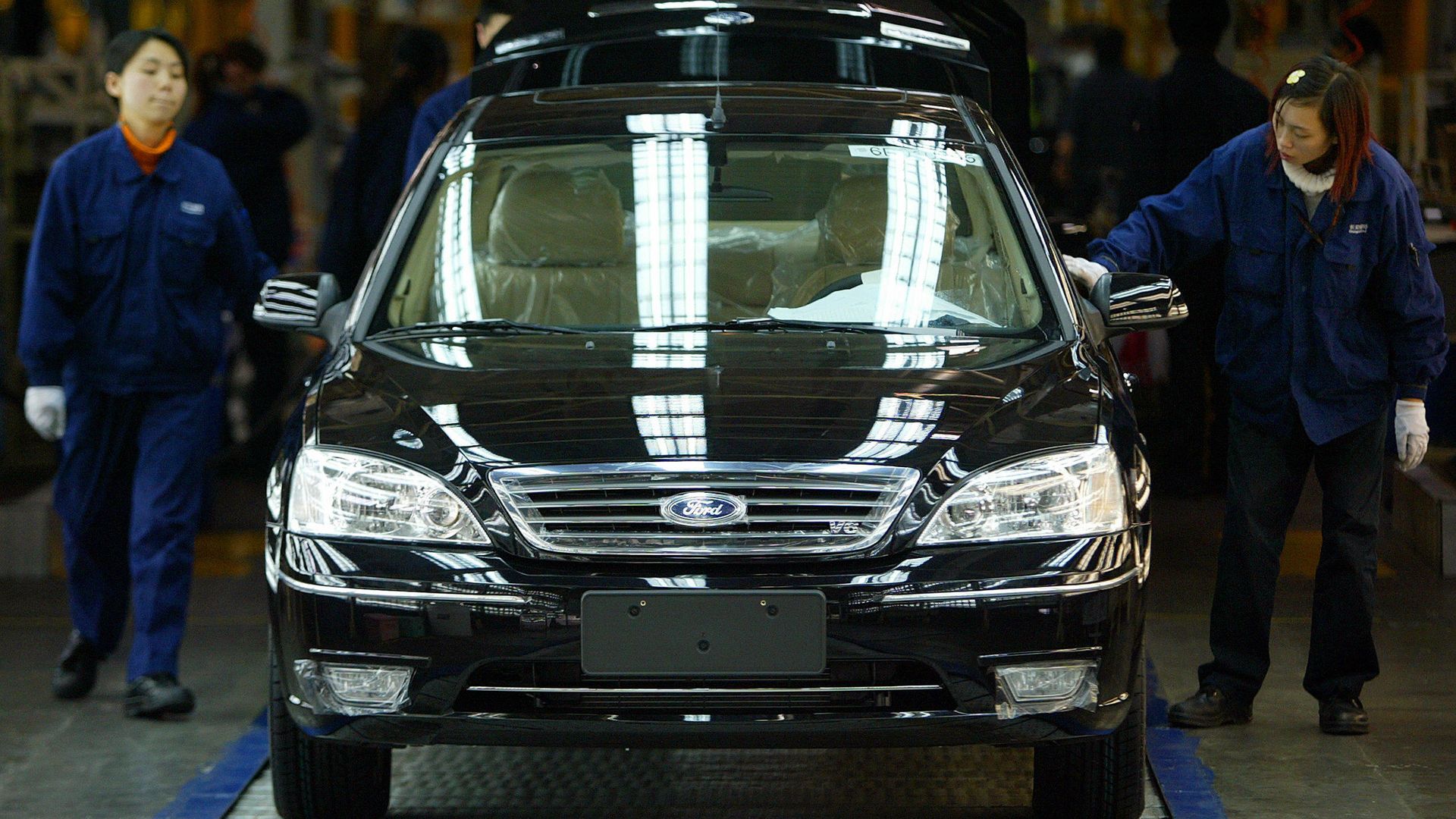 Two women workers take a final inspection on a Ford car on the production line at the Changan Ford plant in China's southwestern city of Chongqing, 27 March 2006.